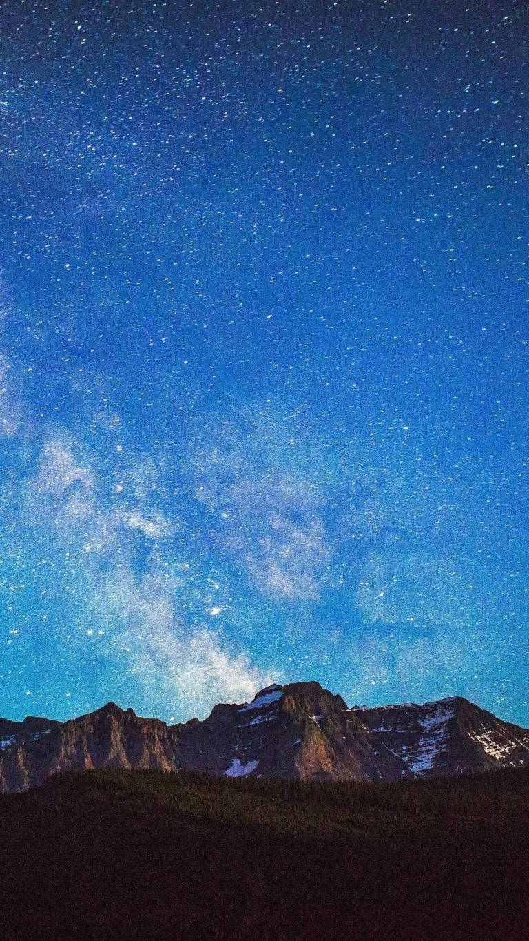 Honor 桌布 壁紙 — 令人嘆為觀止的夜空，充滿無數星星，銀河在崎嶇的積雪山脈上拱起。