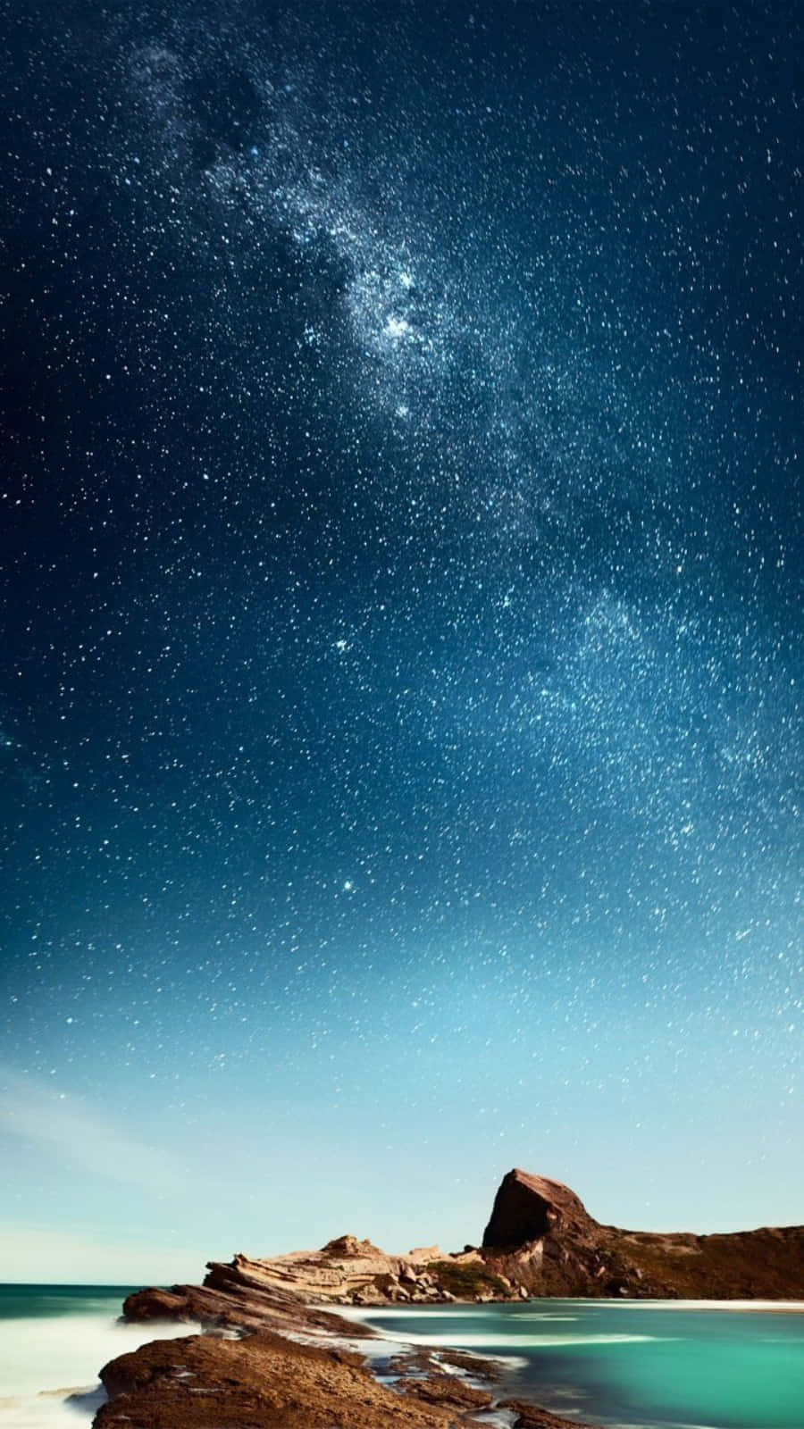 自然 桌布 壁紙 — 令人嘆為觀止的夜空，充滿無數星星，銀河拱跨在平靜的碧綠海洋和崎嶇的海岸岩石之上。