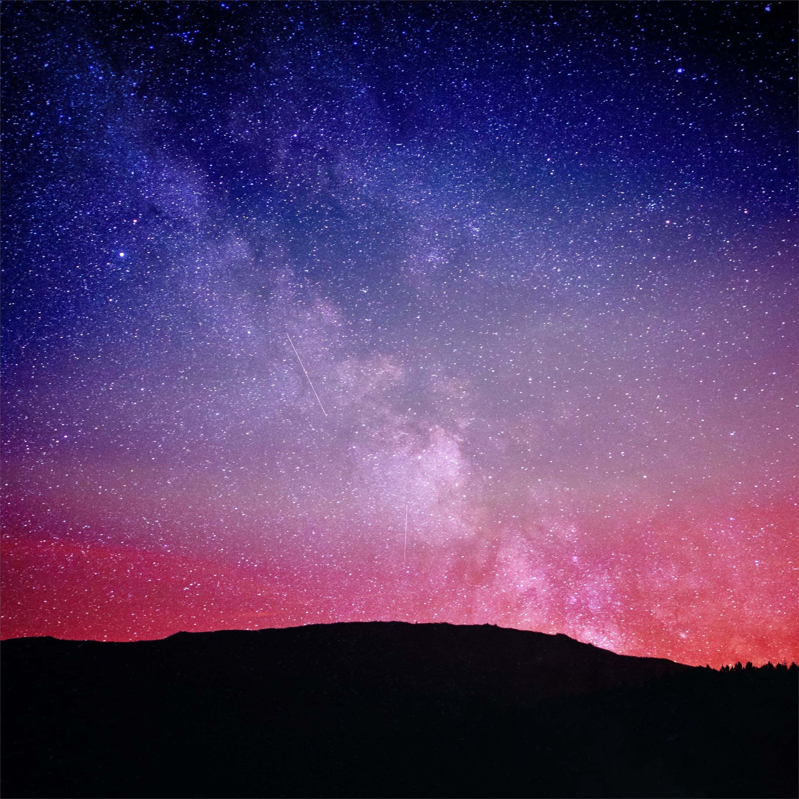Pink iPad Pro 桌布 壁紙 — 令人嘆為觀止的夜空，滿天繁星，銀河在黑暗的山脈輪廓上拱起。