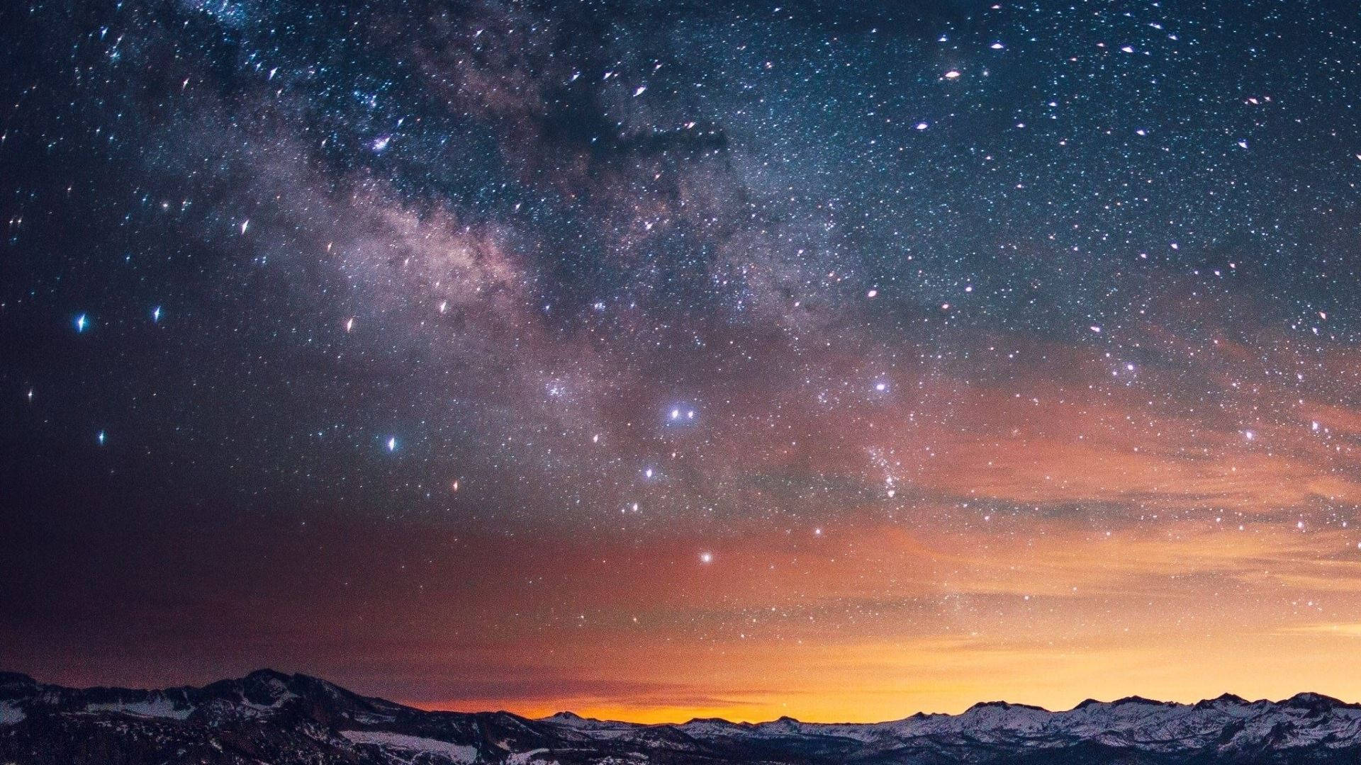 View 桌布 壁紙 — 令人嘆為觀止的夜空，滿天繁星和銀河在暮色中拱起於積雪覆蓋的山脈之上。