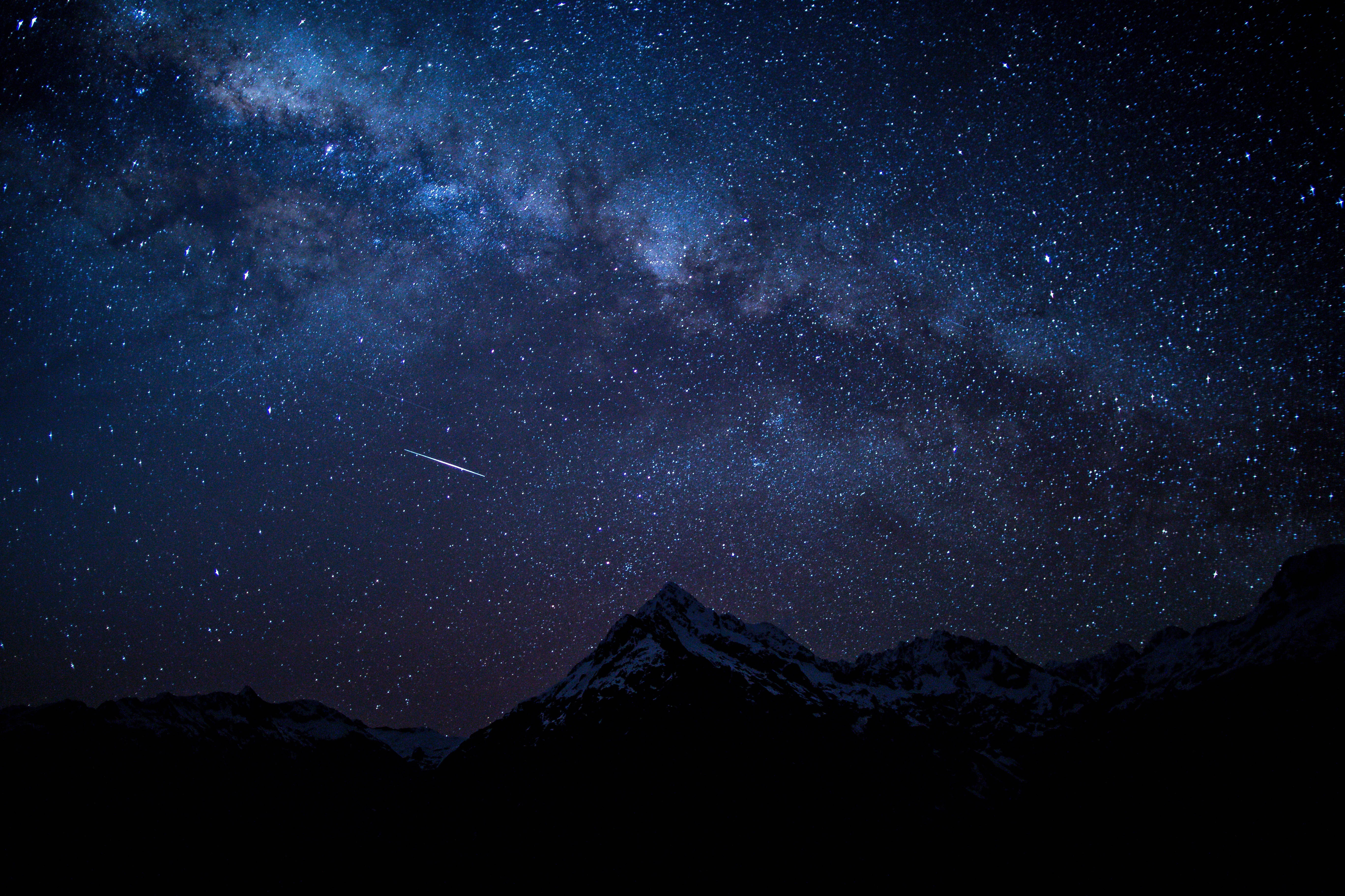 Starry 桌布 壁紙 — 令人嘆為觀止的夜空，滿天繁星和銀河拱起在積雪的山峰之上，一顆流星劃過天際。