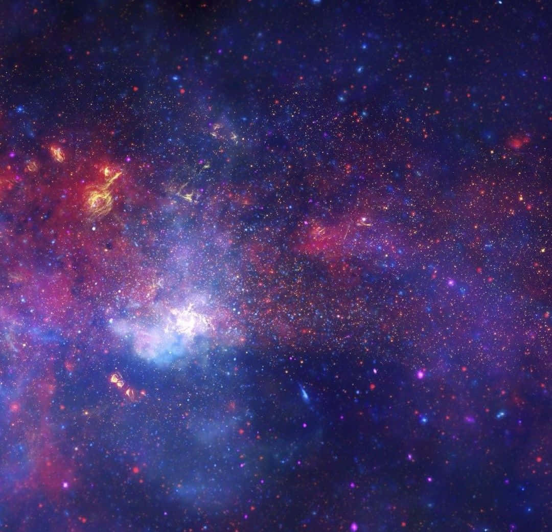 Galactic Center 桌布 壁紙 — 令人嘆為觀止的宇宙景觀，充滿了在繁星點點的黑暗廣闊背景下閃耀著鮮豔紫色、紅色和藍色的旋轉星雲。