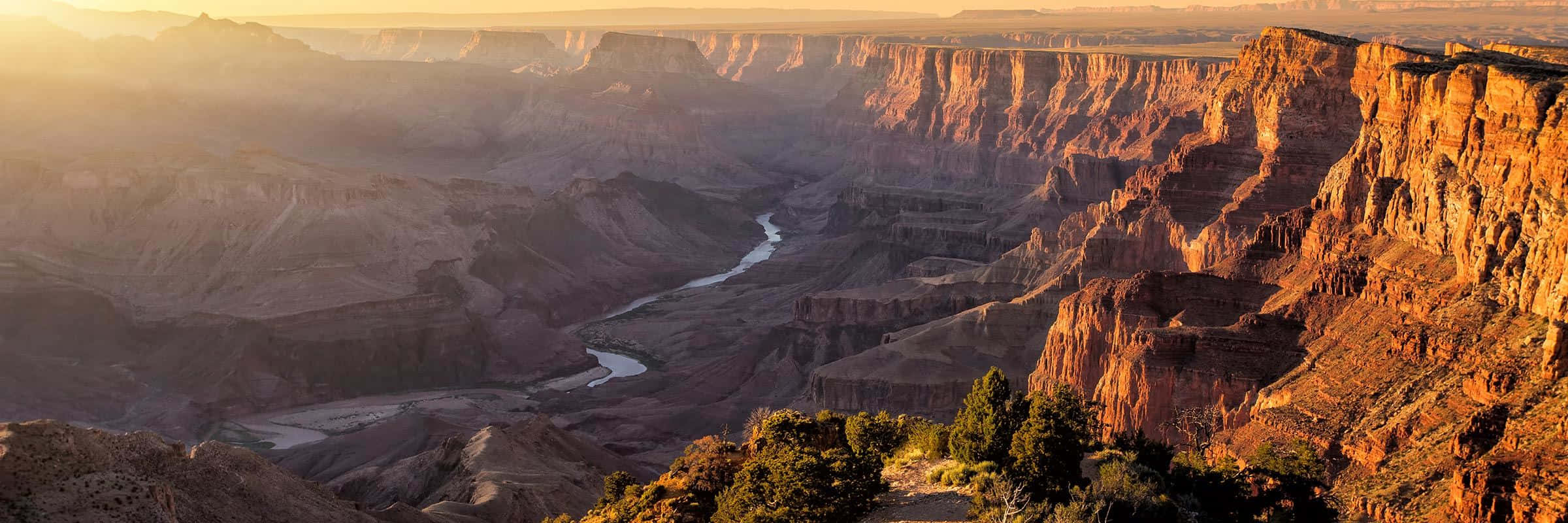 grand canyon 桌布 壁紙 — 令人嘆為觀止的日出照亮了廣闊的紅色峽谷，一條蜿蜒的河流在其深處切割而過。