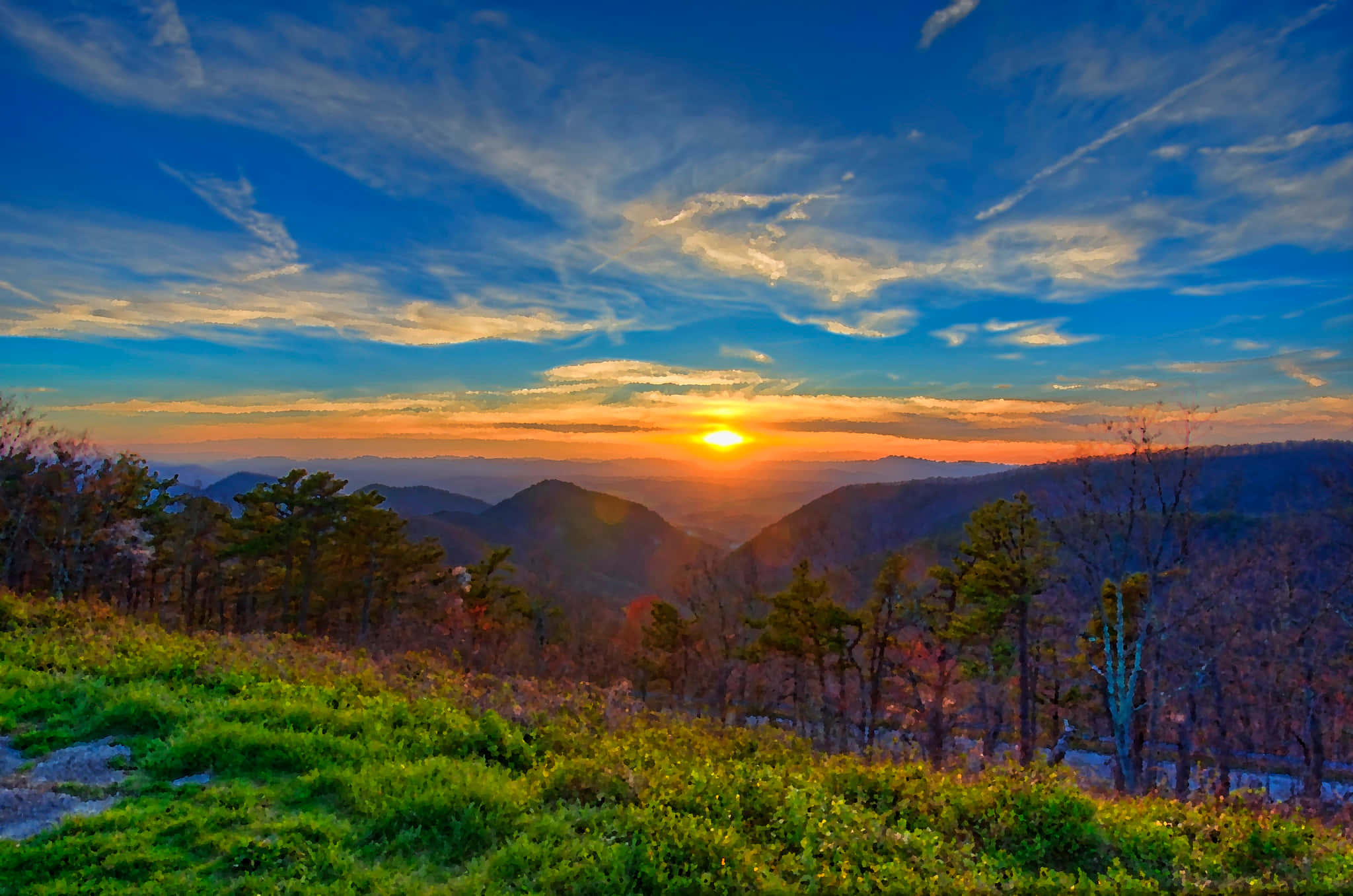 Blue Ridge Mountains 桌布 壁紙 — 令人嘆為觀止的日落，映照在連綿起伏的山巒之上，鮮豔的橙色太陽將溫暖的光芒灑落在層層疊疊的山峰和綠色的前景上。