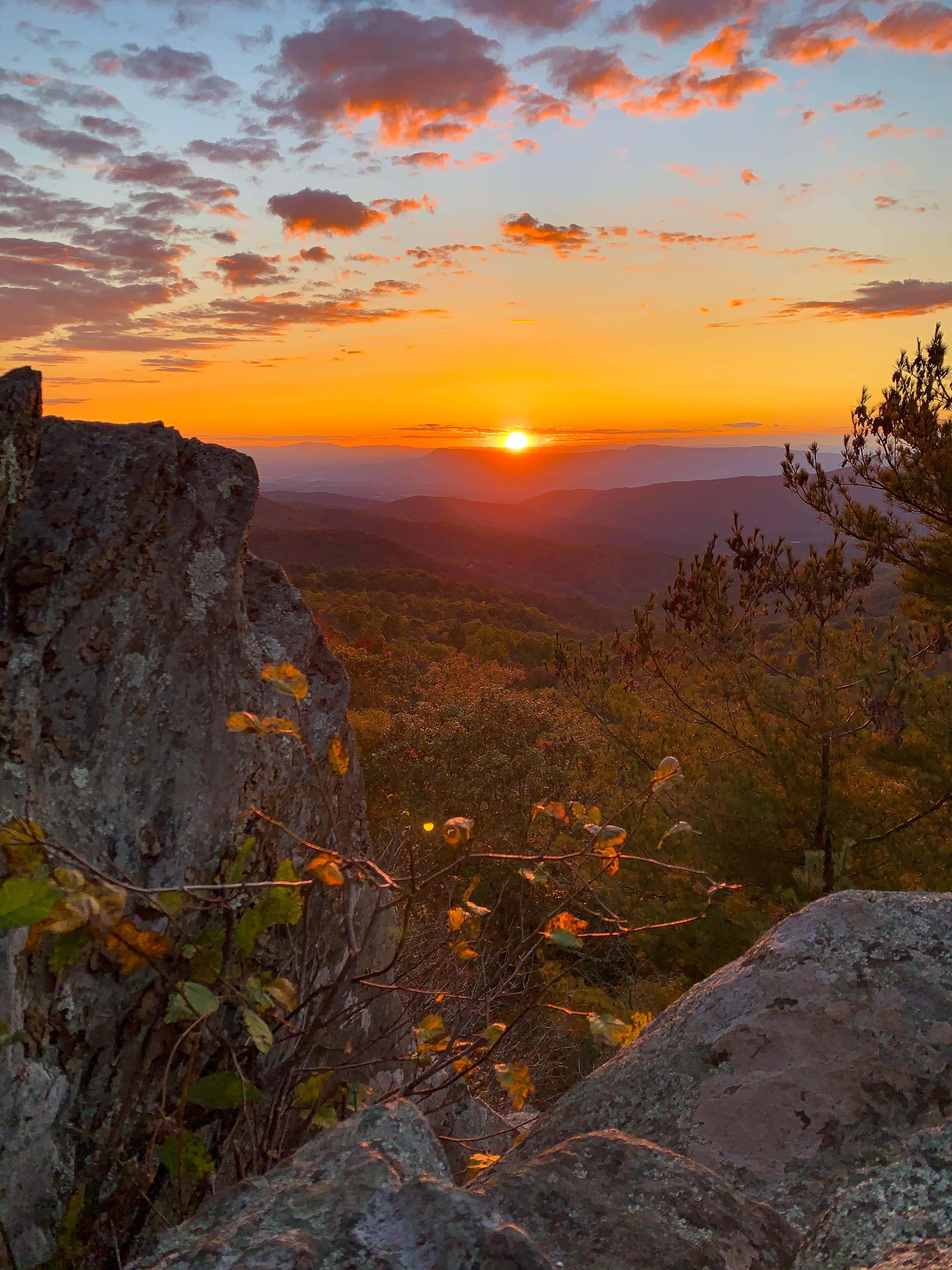 Blue Ridge Mountains 桌布 壁紙 — 令人嘆為觀止的日落，映照在連綿起伏的山巒上，四周環繞著崎嶇的岩石和閃爍著溫暖色調的秋葉。