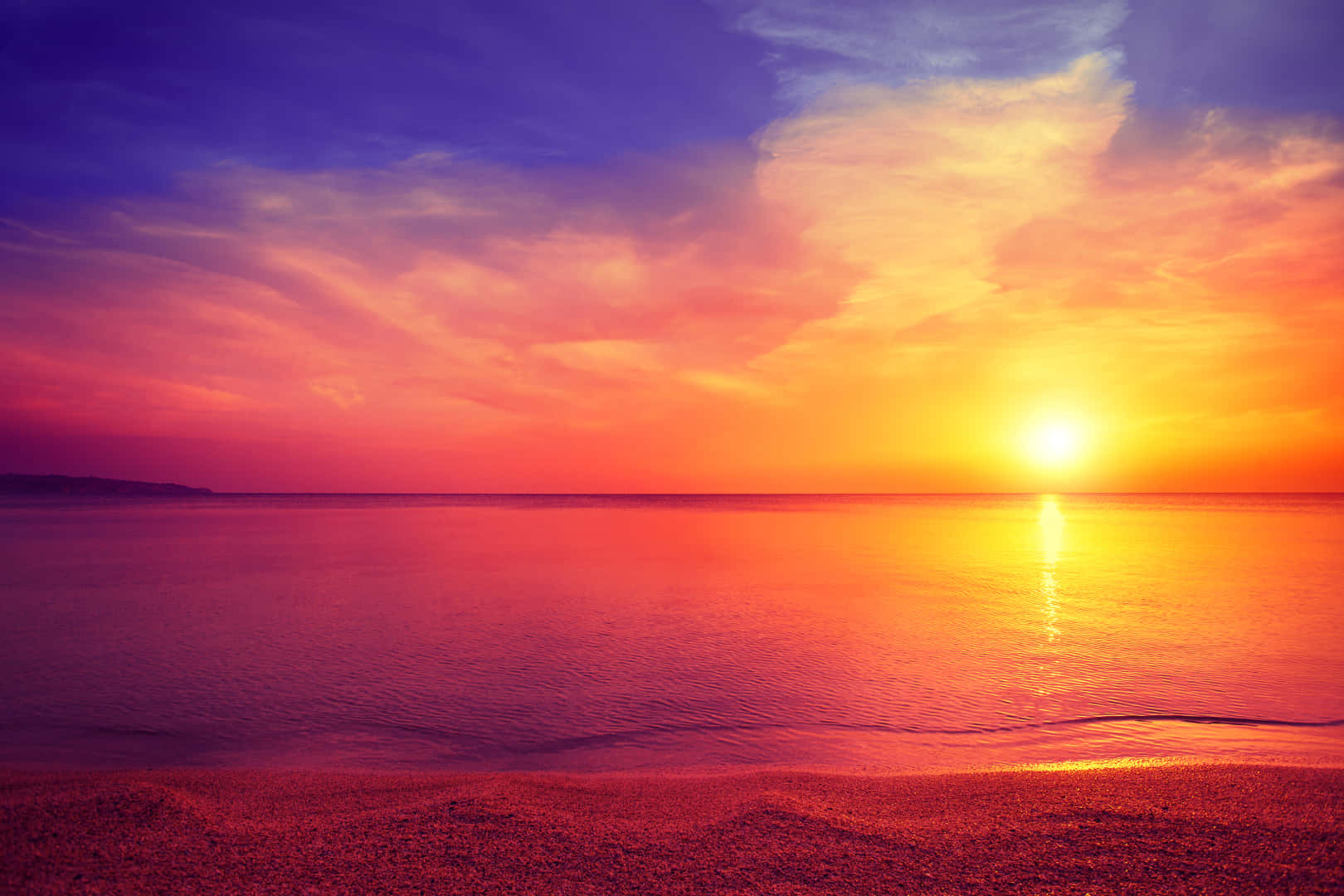 Calming Desktop 桌布 壁紙 — 令人嘆為觀止的日落將天空和海洋染成火熱的橙色和深紫色，太陽沉入地平線以下。