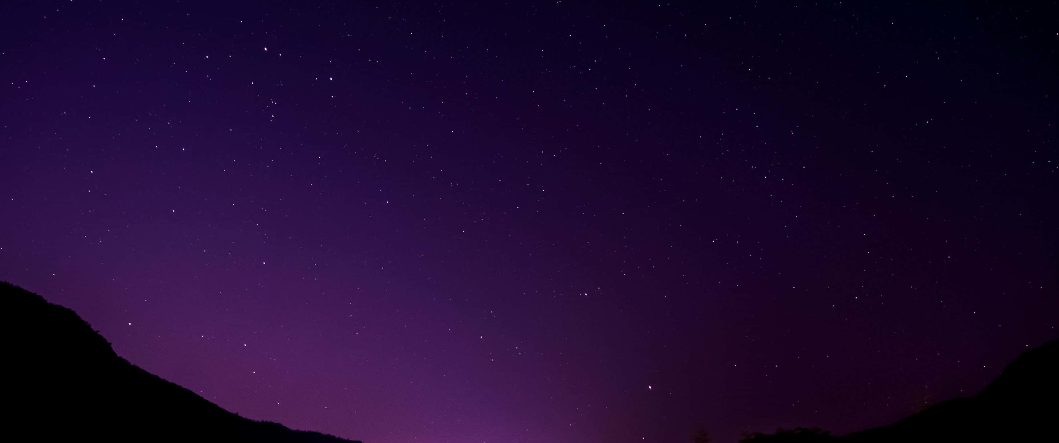桌布 壁紙 — 令人嘆為觀止的星空夜景，帶有深紫色漸變和下方輪廓分明的山脊。