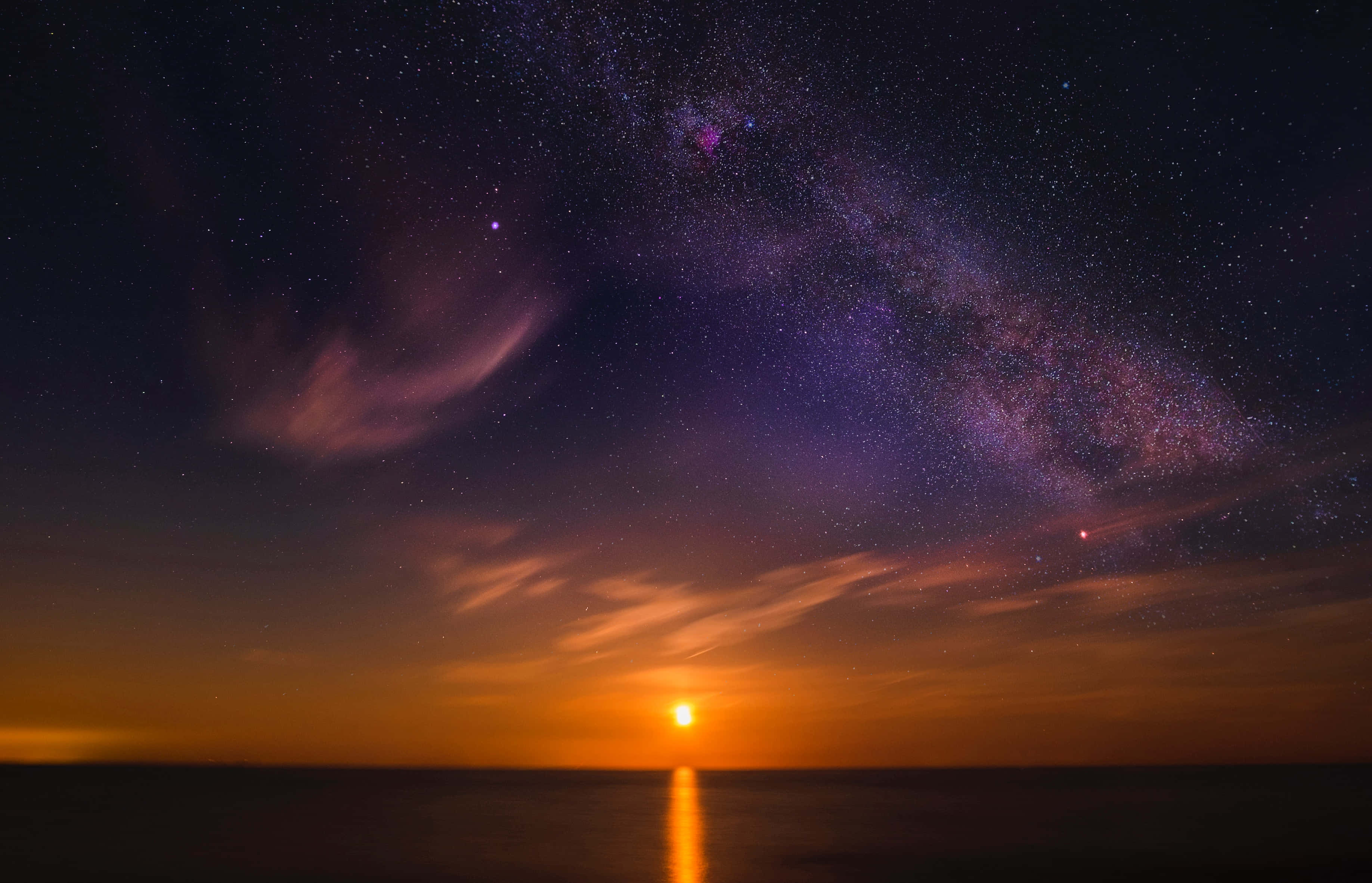 Colorful Sky 桌布 壁紙 — 令人嘆為觀止的暮色天空，銀河在平靜海面上反射的夕陽餘暉上方劃出一道弧線。