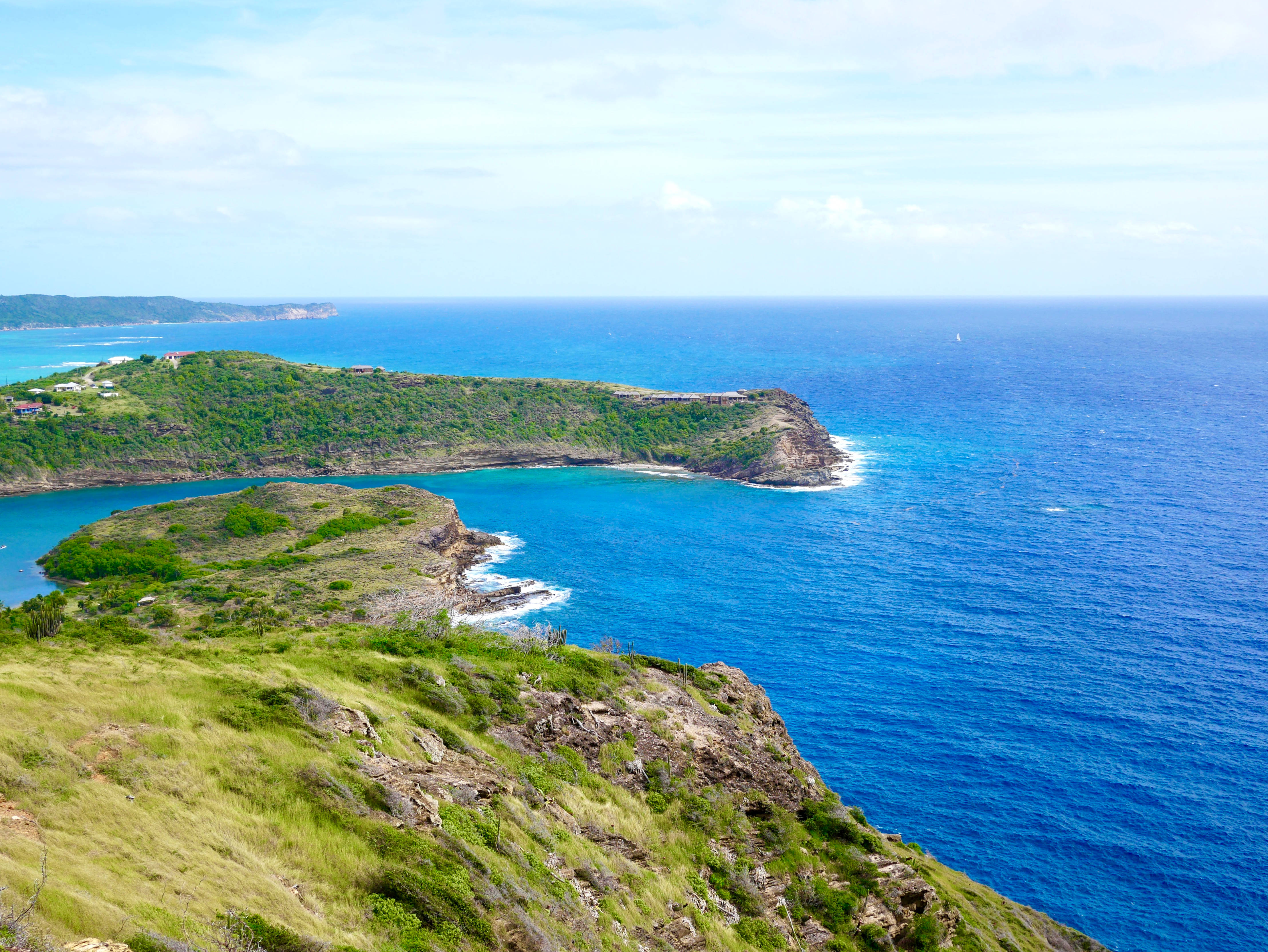 Antigua And Barbuda 桌布 壁紙 — 令人嘆為觀止的海岸景色，碧綠的海水拍打崎嶇的懸崖，上方是明亮的藍天。