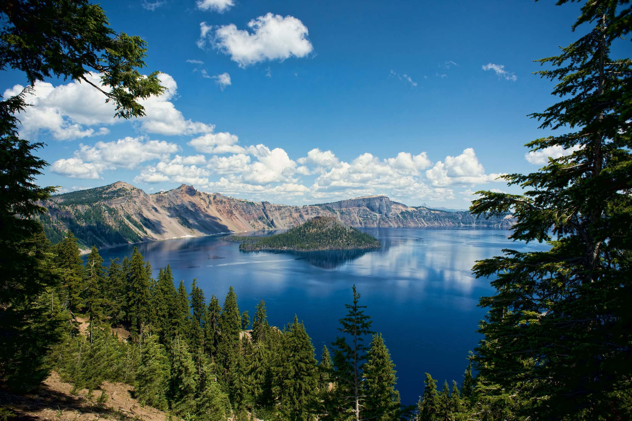 Lake 桌布 壁紙 — 令人嘆為觀止的火山口湖景色，被常綠樹環繞，在明亮的藍天和蓬鬆的白雲下。
