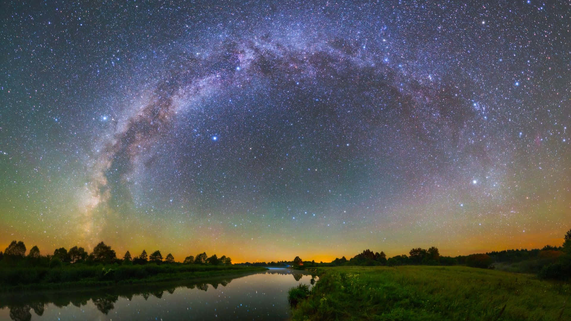 星空動畫 桌布 壁紙 — 令人嘆為觀止的銀河拱橋在平靜的河流上，反射出星星和發光的地平線。