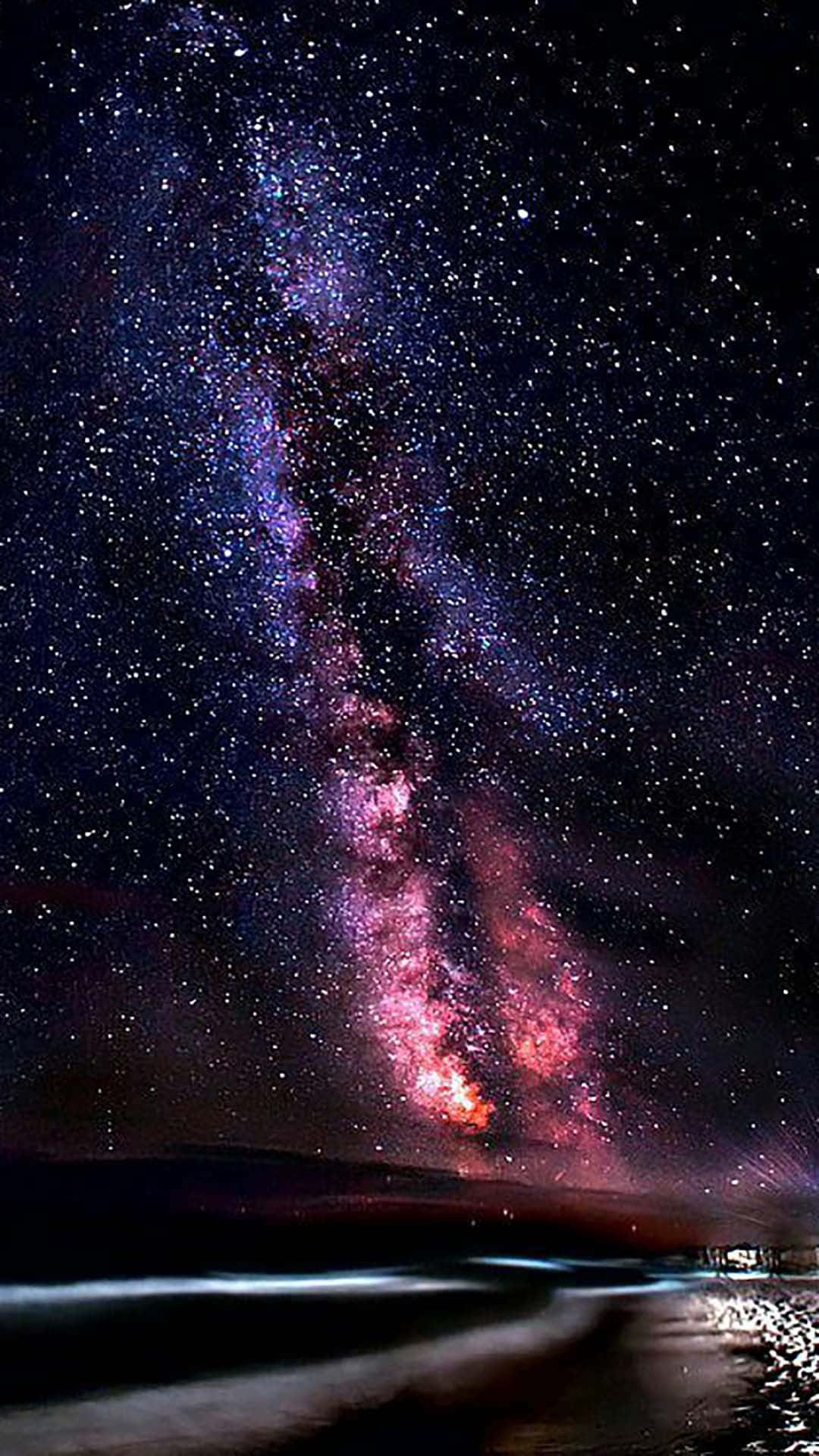 Stars 桌布 壁紙 — 令人嘆為觀止的銀河系景觀，在夜晚的黑暗沙灘上閃耀著鮮豔的紫色和粉紅色。
