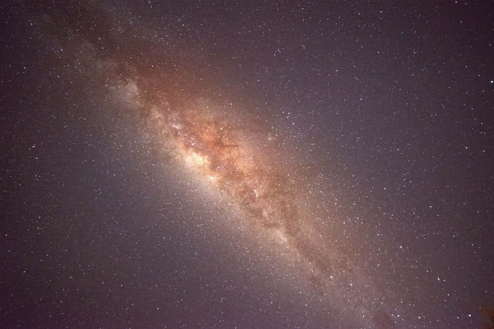 太空 桌布 壁紙 — 令人嘆為觀止的銀河系景觀，在深紫色夜空中閃耀著金色塵埃和無數星星。
