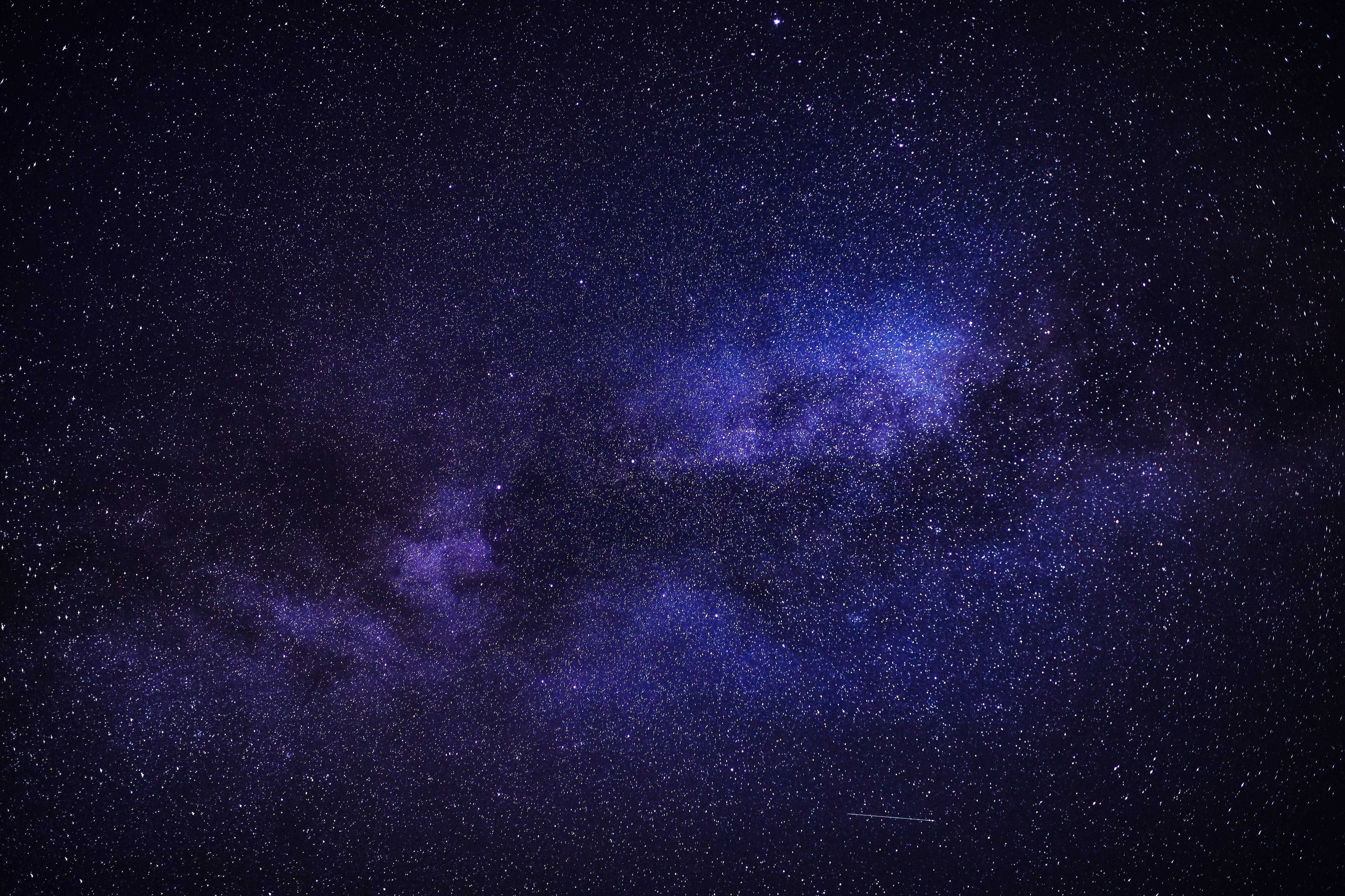 宇宙美學 桌布 壁紙 — 令人嘆為觀止的銀河系景觀，在深紫色和藍色中閃耀，映襯著繁星點點的夜空。