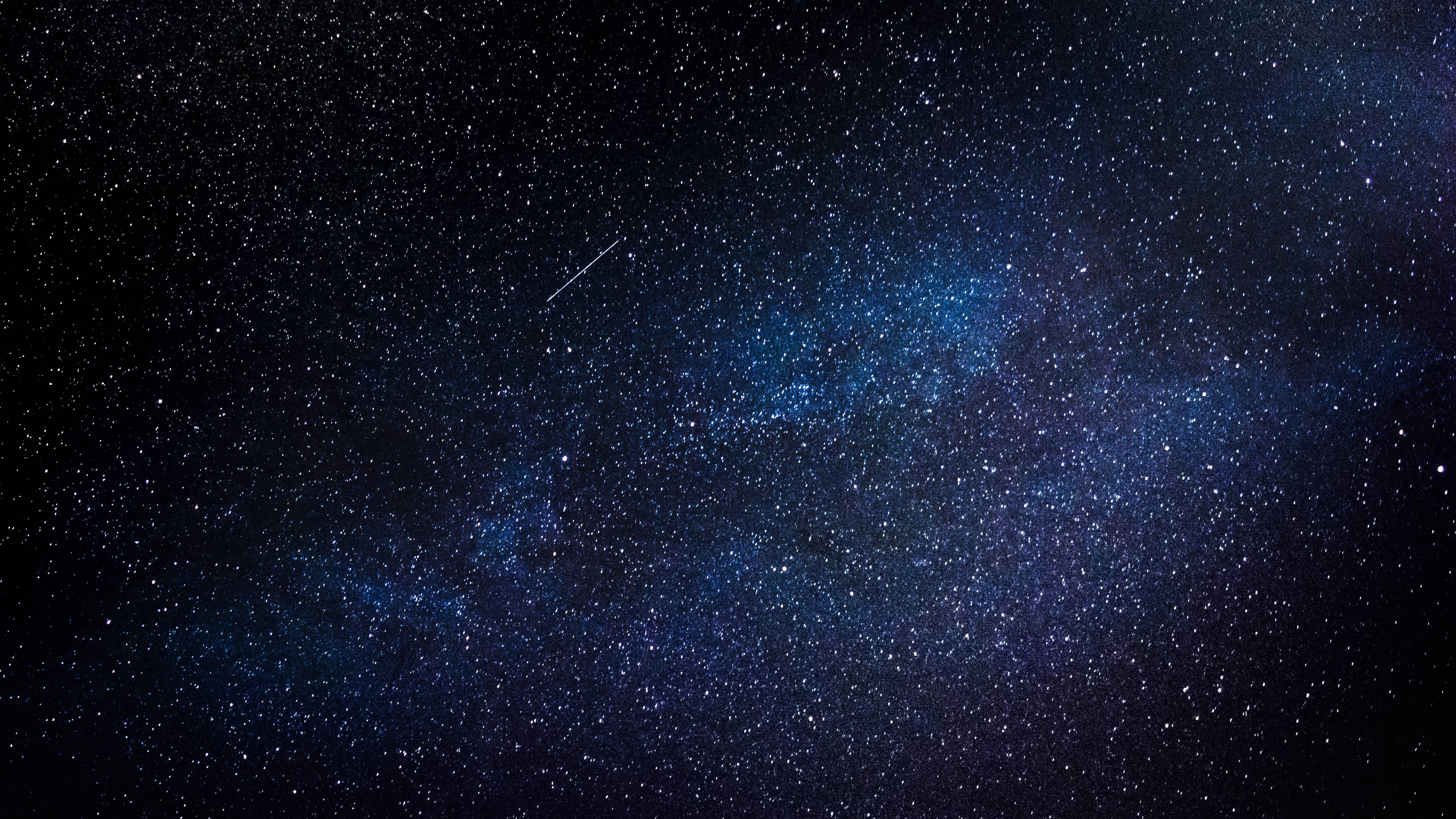 星際異攻隊 桌布 壁紙 — 令人嘆為觀止的銀河系景觀，在深藍色中閃耀，背景是繁星點點的夜空，一顆微弱的流星劃過天際。