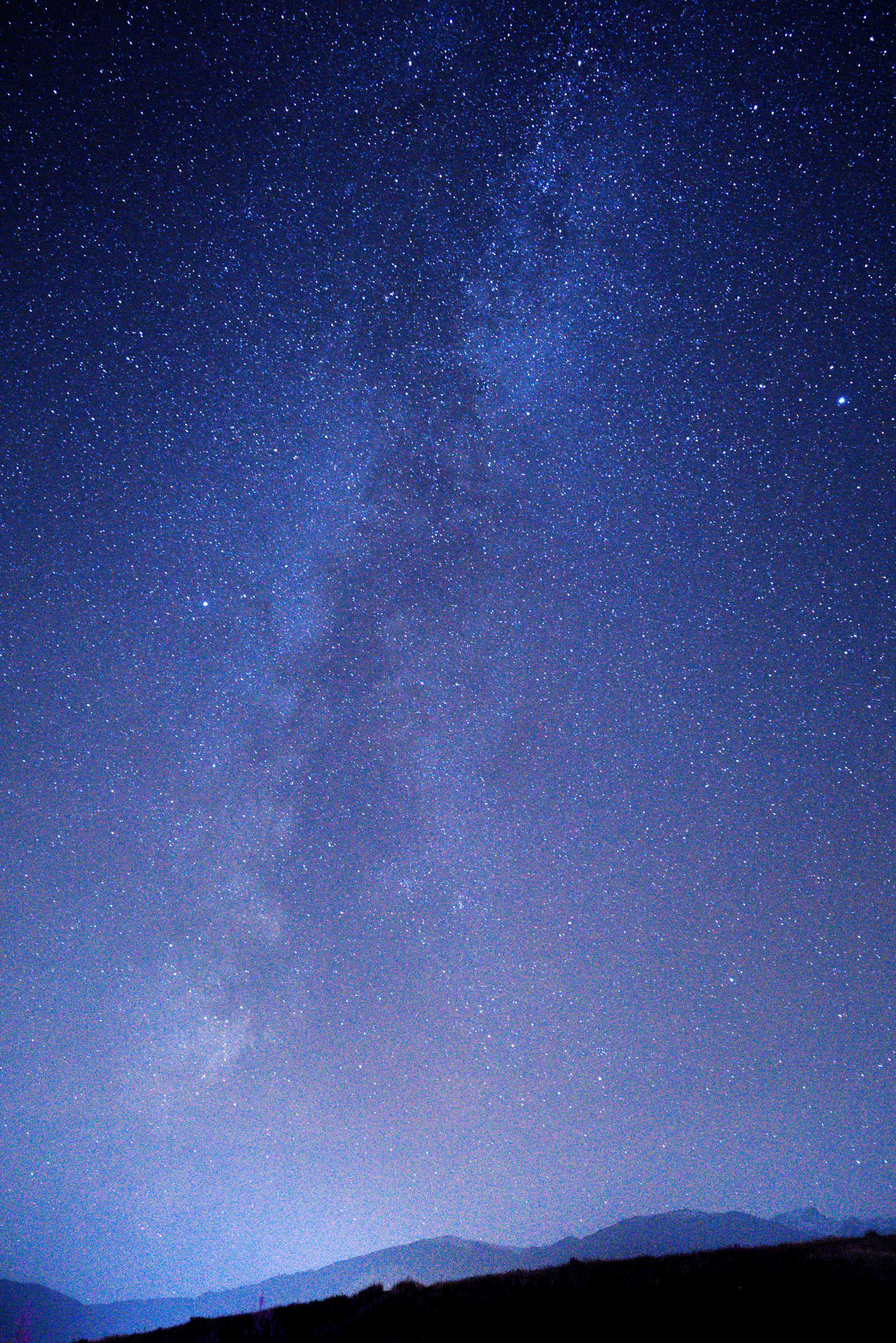 Starry Sky 桌布 壁紙 — 令人嘆為觀止的銀河系景觀，在深藍色夜空下，橫跨在黑暗山脈剪影之上。
