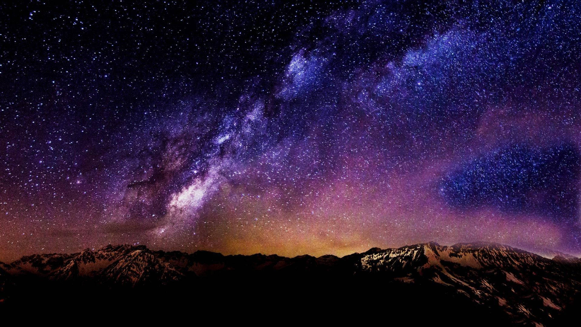 Sky HD 桌布 壁紙 — 令人嘆為觀止的銀河系景觀，在白雪覆蓋的山峰之上，拱形橫跨於紫色和藍色的星空夜空。