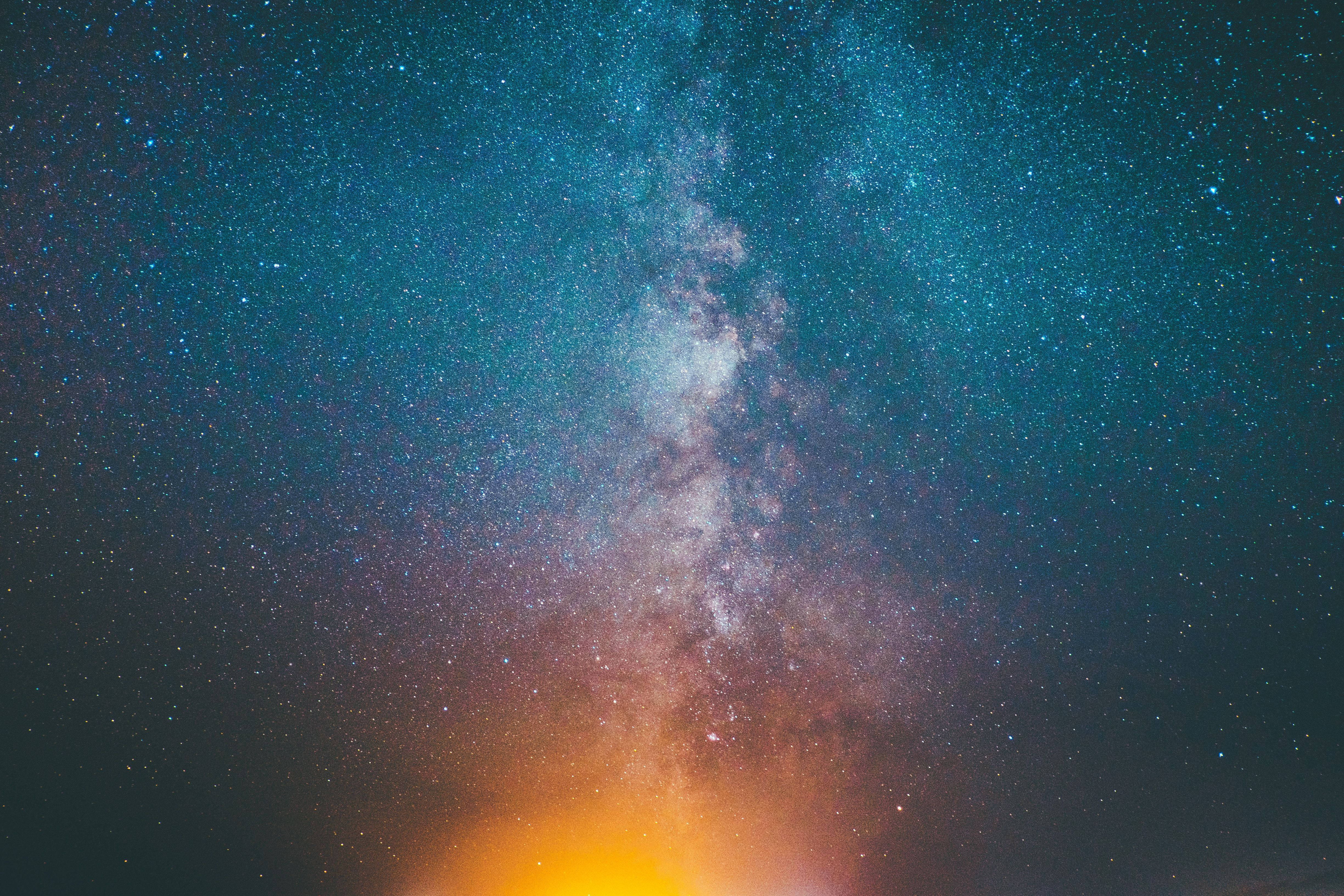 Milky 桌布 壁紙 — 令人嘆為觀止的銀河系景觀，在繁星點點的夜空中散發著青綠色、橙色和白色的宇宙色彩。