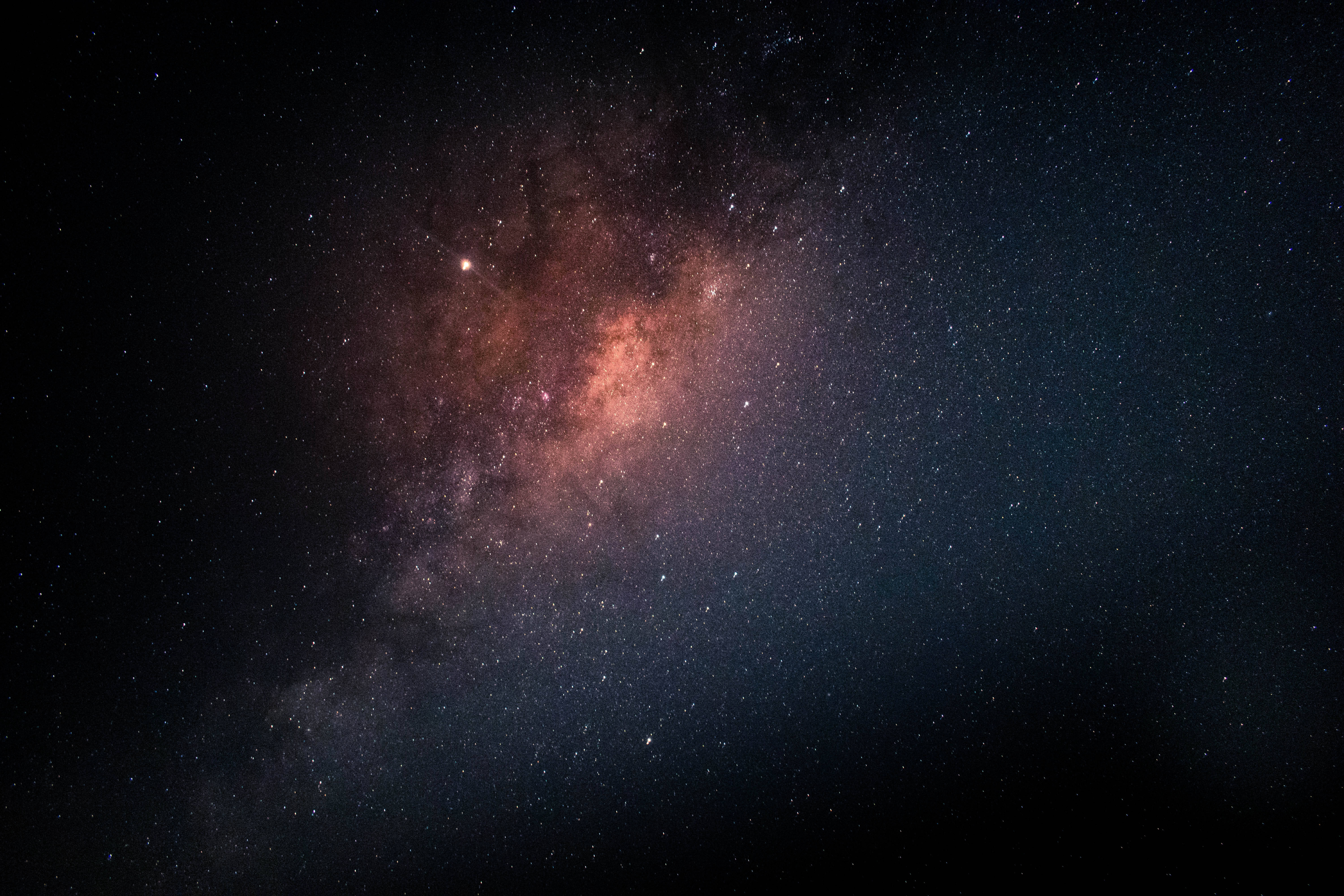 Starry Sky 桌布 壁紙 — 令人嘆為觀止的銀河系景觀，在繁星點點的夜空中閃耀著粉紅色和橙色的星雲。