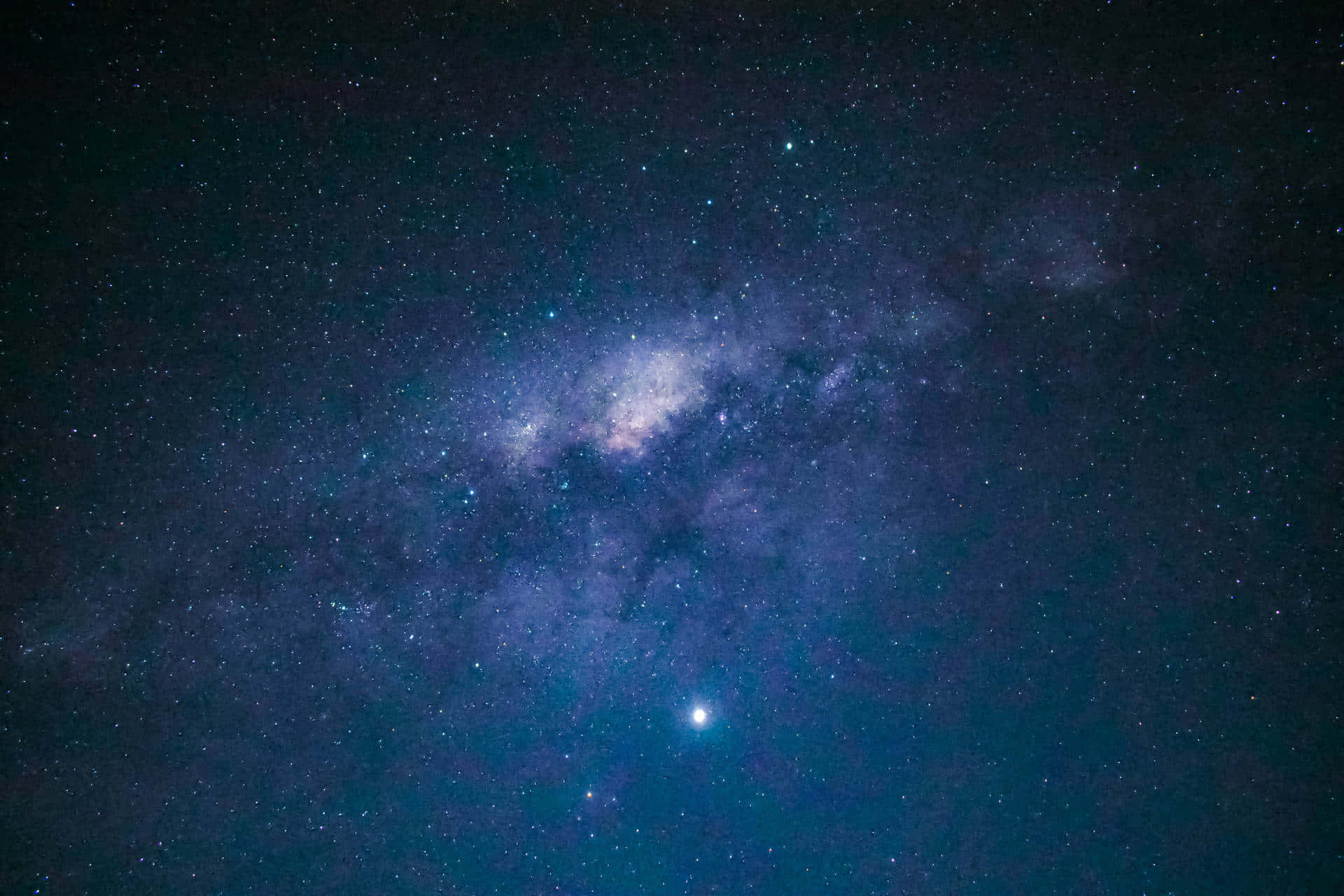 Starry Sky 桌布 壁紙 — 令人嘆為觀止的銀河系景觀，在繁星點點的夜空中散發著紫色和藍色的光芒。