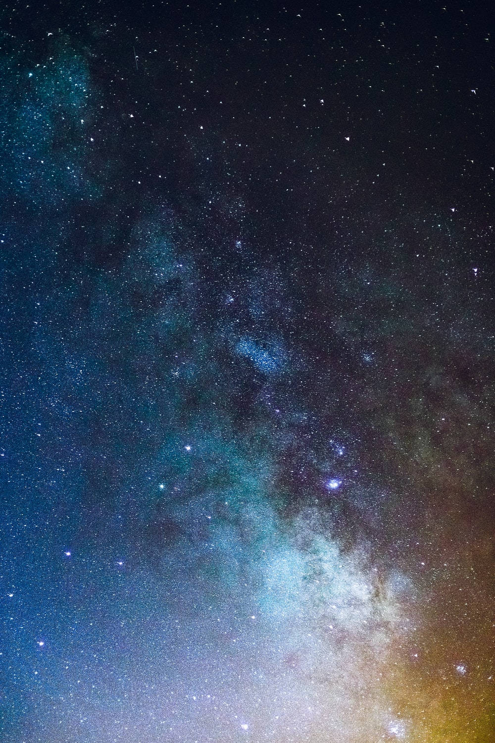 夜空 桌布 壁紙 — 令人嘆為觀止的銀河系景觀，在繁星點點的夜空下閃耀著鮮豔的藍色和金色光芒。
