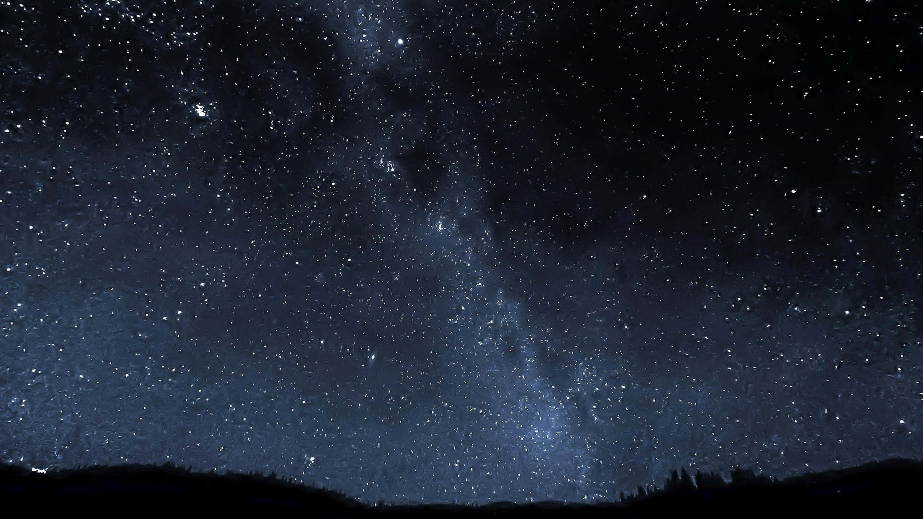 Stars 桌布 壁紙 — 令人嘆為觀止的銀河系景觀，在黑暗的山脈剪影上方閃爍著無數星星。