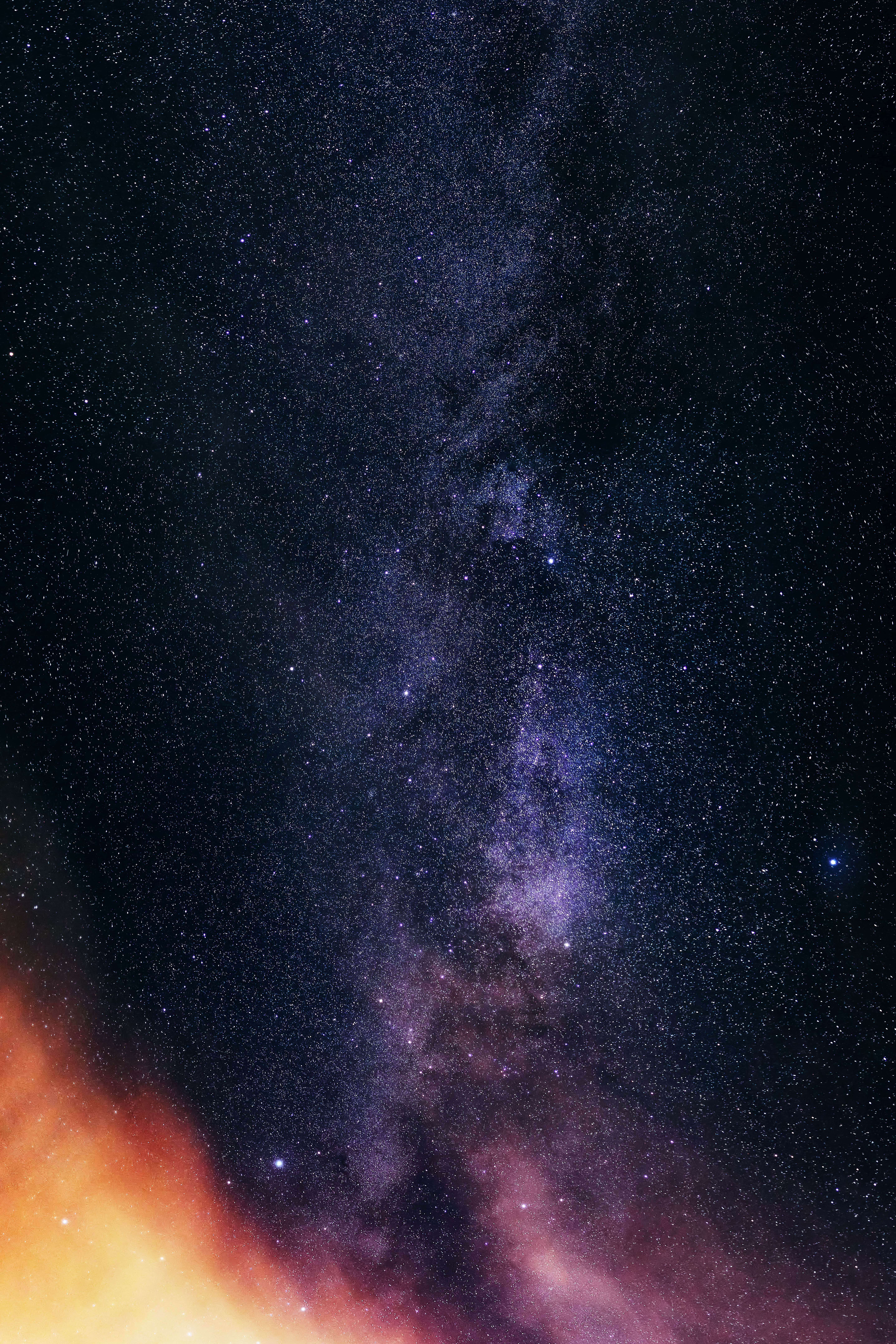 Starry Sky 桌布 壁紙 — 令人嘆為觀止的銀河系景觀，在黑暗的天空中散發著紫色和藍色的光芒，下方由熾熱的橙色雲彩框住。