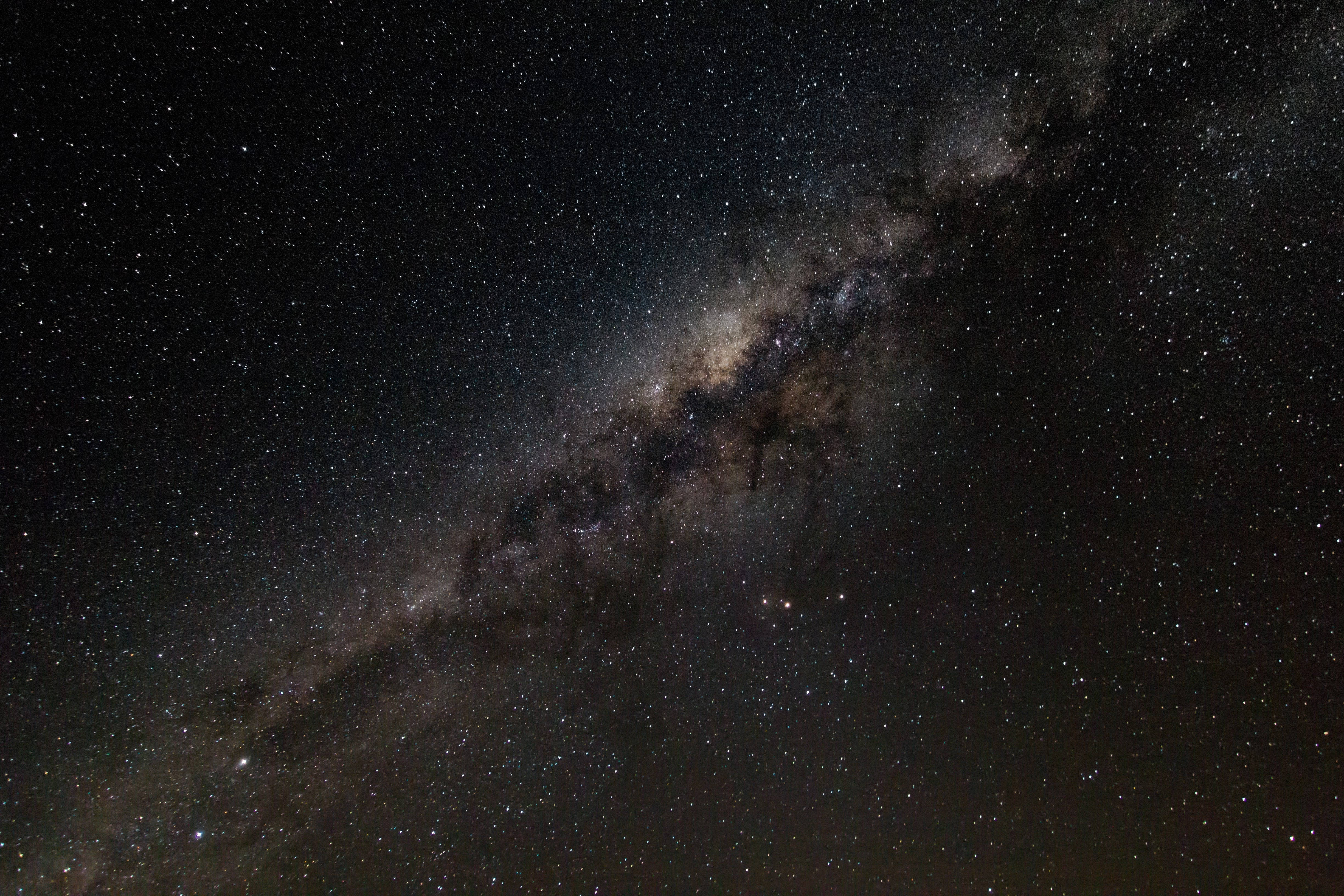 Milky 桌布 壁紙 — 令人嘆為觀止的銀河系景觀，斜跨滿天星斗的夜空，有旋轉的塵埃雲和發光的星雲。