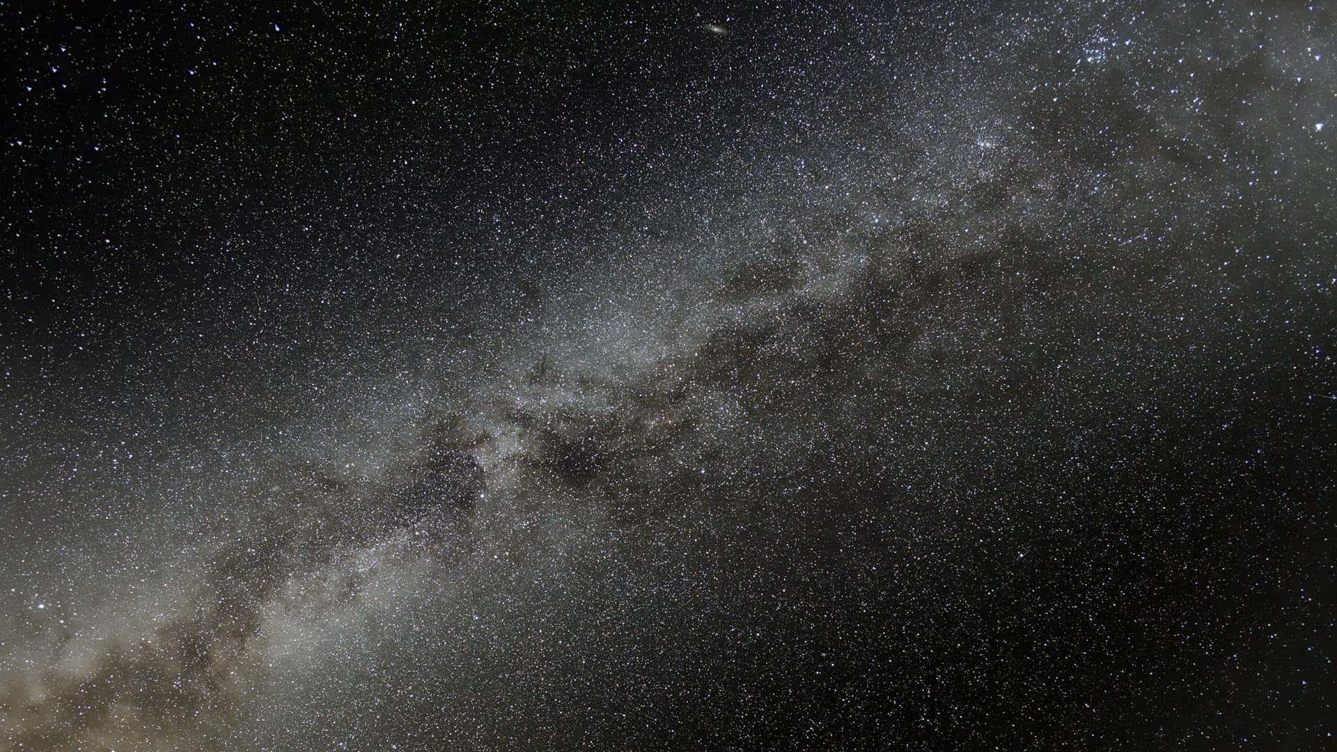 Black Macbook 桌布 壁紙 — 令人嘆為觀止的銀河系景觀，橫跨佈滿星星的夜空，帶有宇宙塵埃雲。