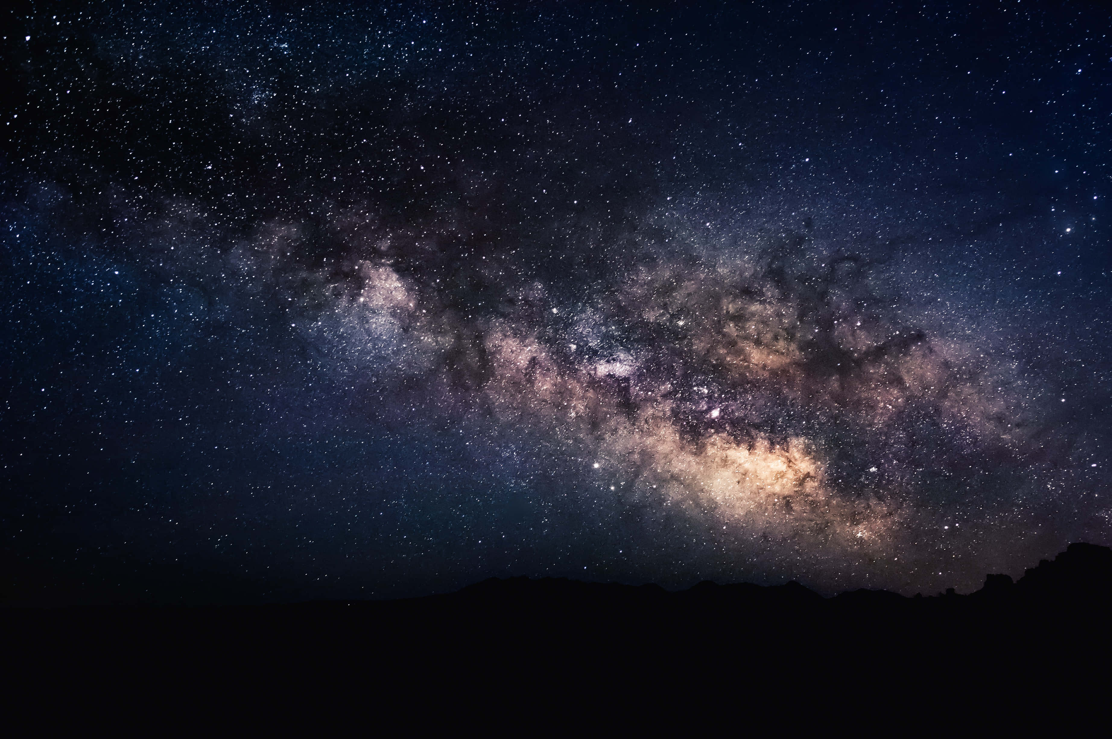 Aesthetic Nature Tumblr 桌布 壁紙 — 令人嘆為觀止的銀河系景觀，橫跨在佈滿星星的夜空之上，襯托著黑暗的山巒輪廓。