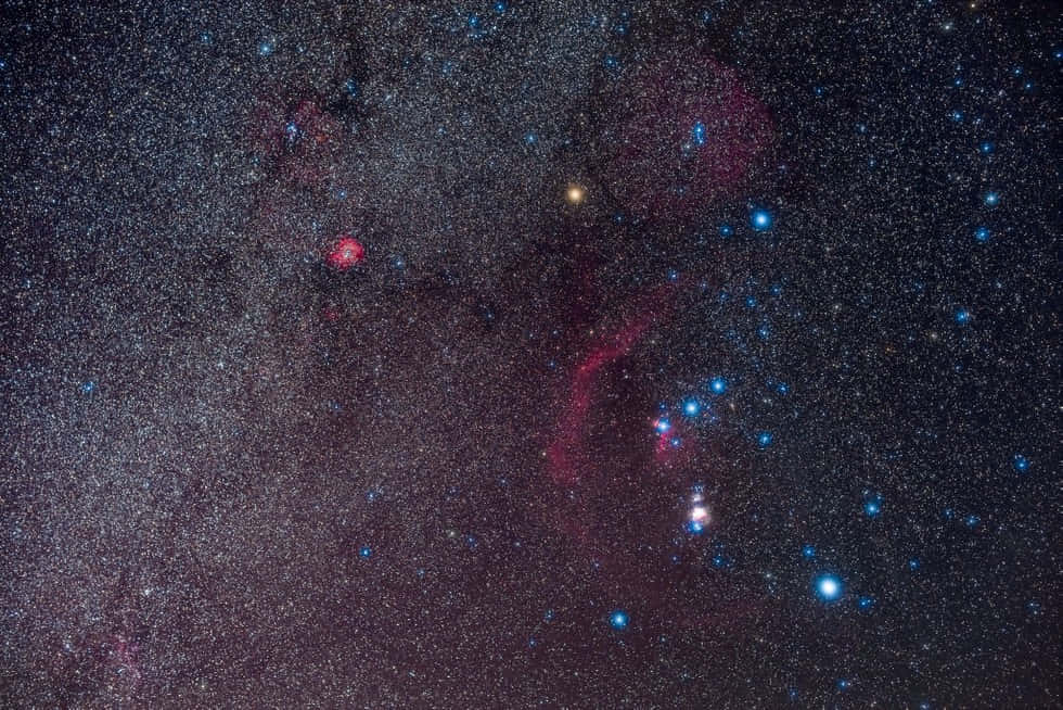 Starry Sky 桌布 壁紙 — 令人嘆為觀止的銀河系景觀，發光的紅色和藍色星雲以及無數恆星，映襯著深邃的宇宙黑色背景。
