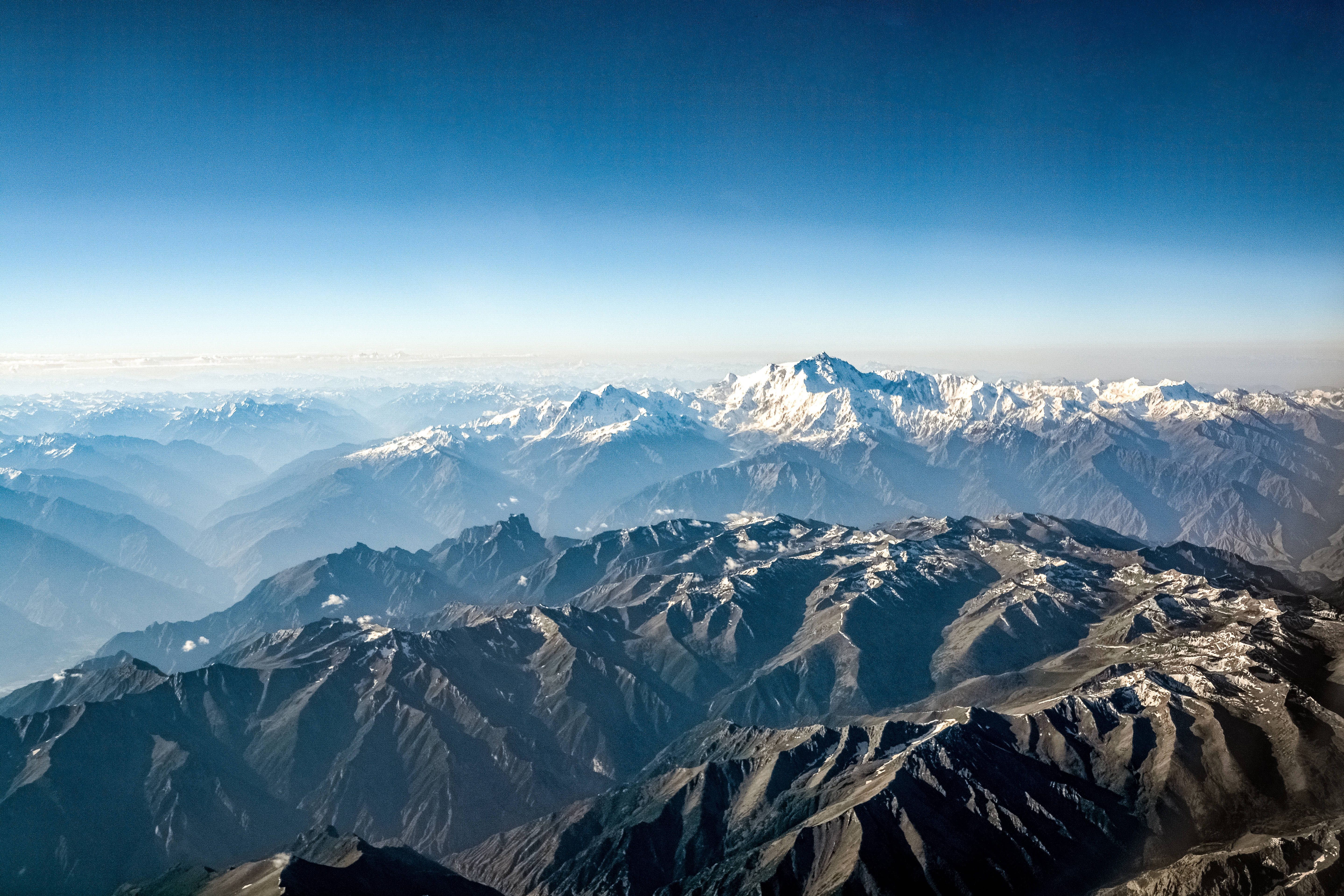 Topography 桌布 壁紙 — 令人嘆為觀止的鳥瞰圖，展現層層疊疊的山脈，白雪覆蓋的山峰在清澈的藍天下。