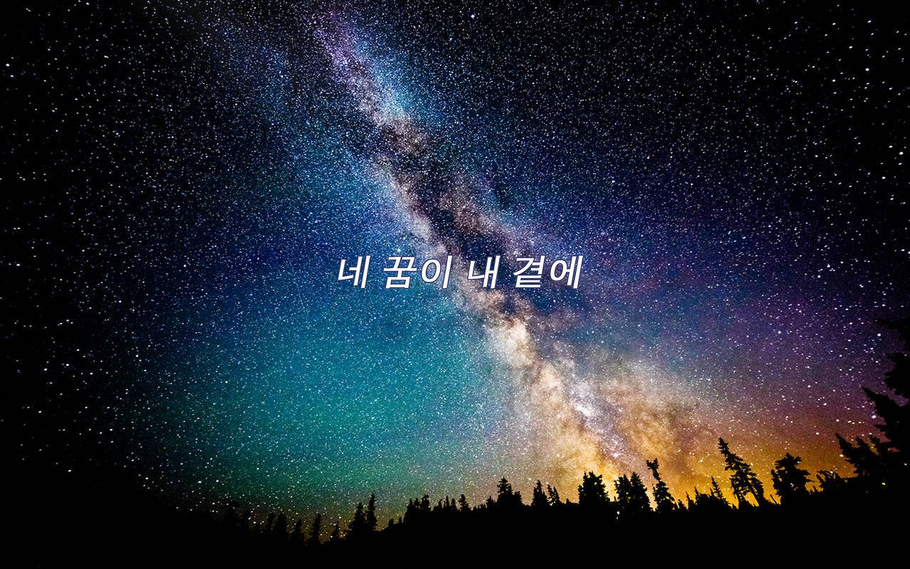 K-pop 桌布 壁紙 — 令人屏息的夜空，佈滿繁星，銀河在黑暗的森林剪影上方拱起。