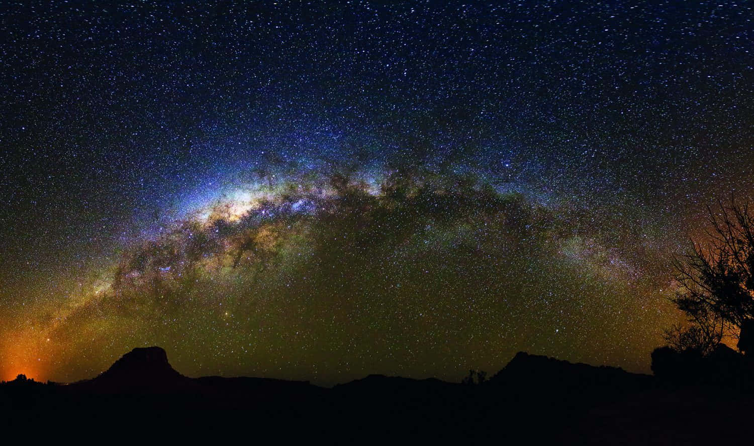 Starry Sky 桌布 壁紙 — 令人屏息的夜空，充滿無數星星，銀河系的發光帶在黑暗的沙漠輪廓上拱起。