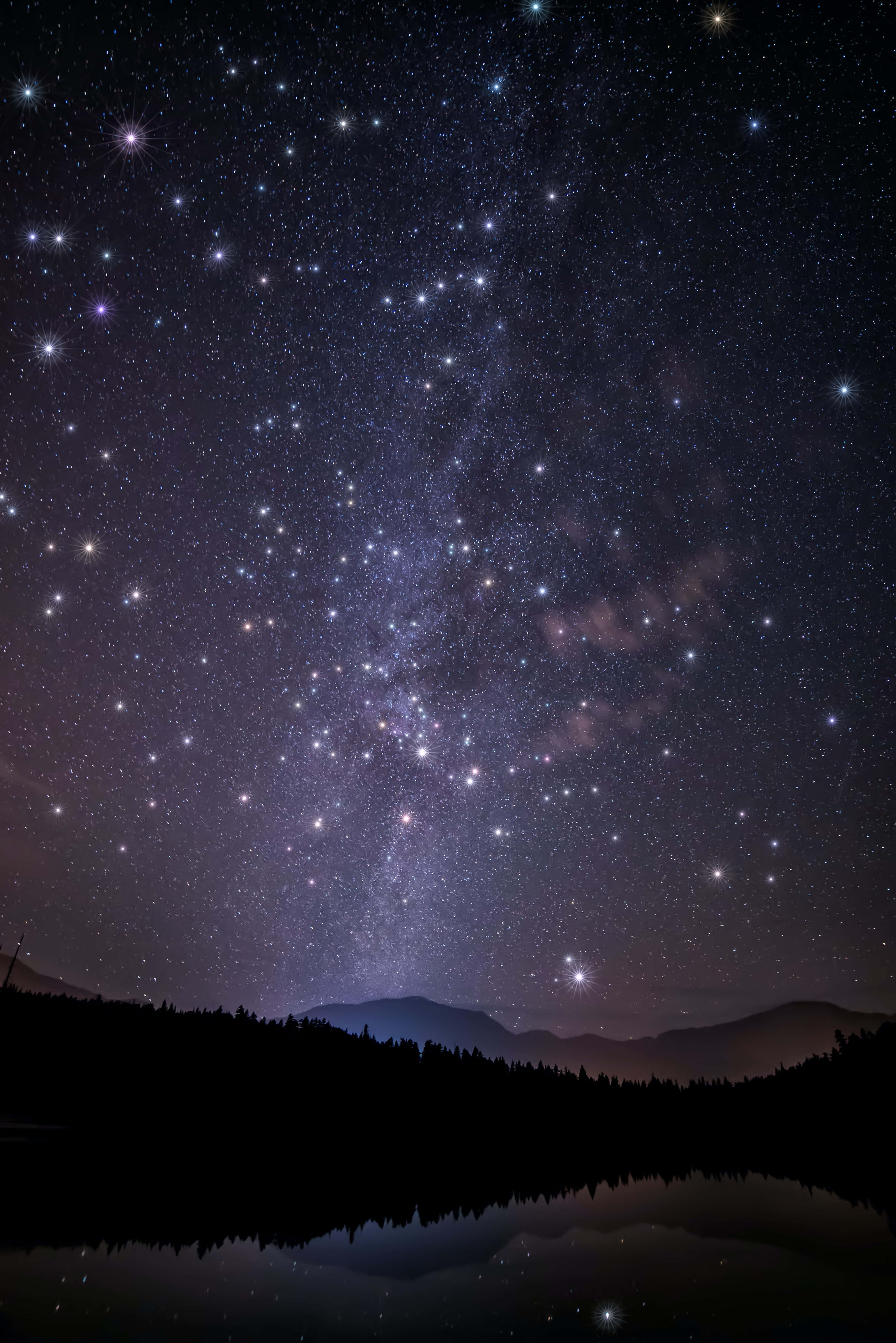 夜空 桌布 壁紙 — 令人屏息的夜空，充滿無數星星，銀河拱起在剪影山脈和寧靜的反射湖面上。