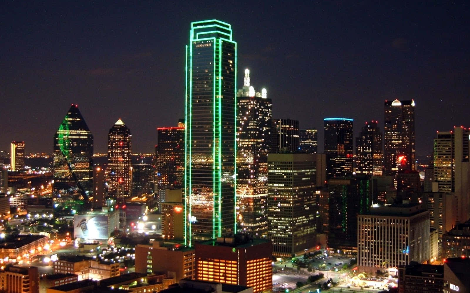 dallas 桌布 壁紙 — 令人目眩的夜景，一座高聳的摩天大樓在黑暗的天空中勾勒出鮮豔的綠色霓虹燈輪廓。