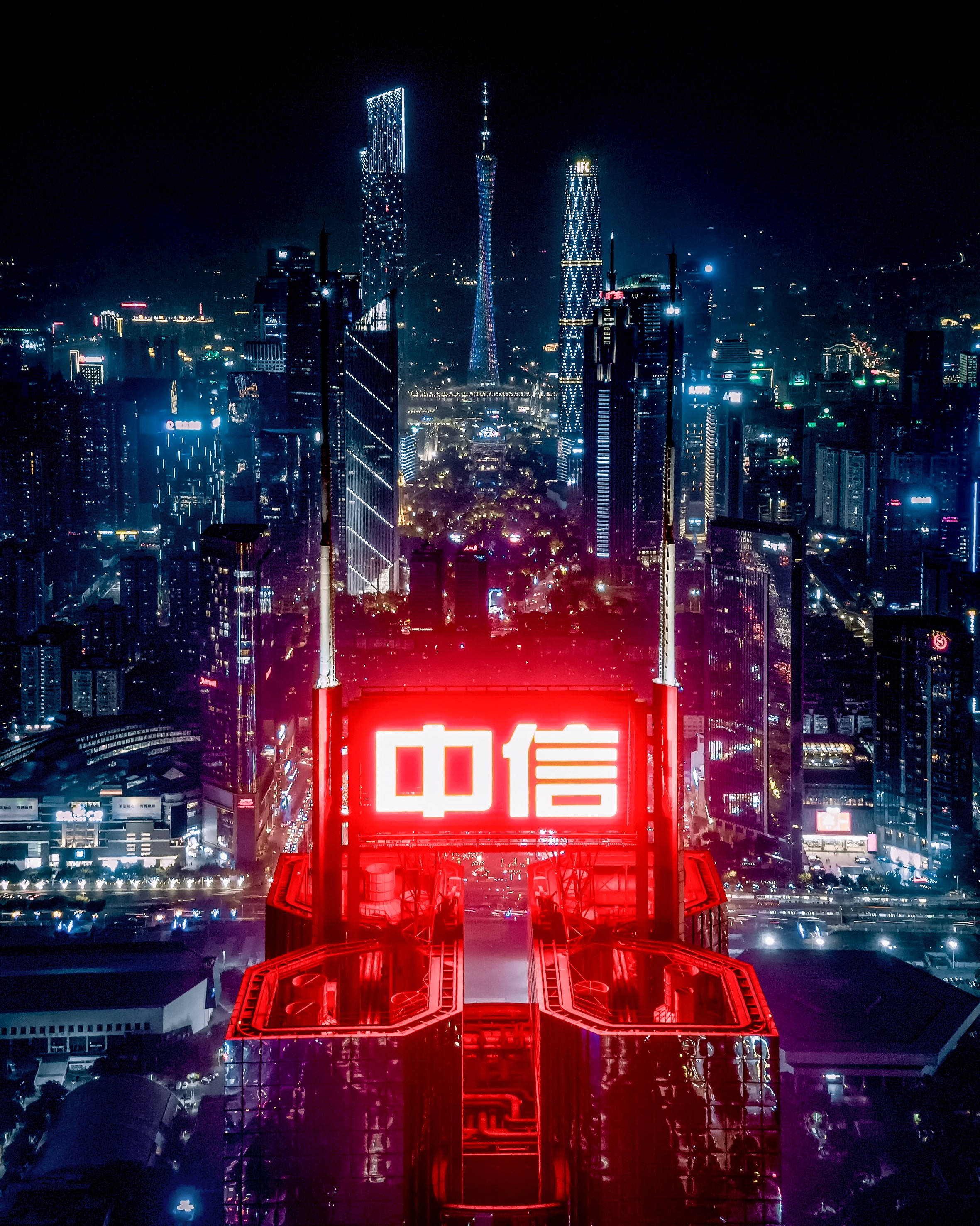 霓虹城市動態圖 桌布 壁紙 — 令人目眩的夜景城市景觀，高聳的摩天大樓和一個突出的紅色霓虹燈招牌在黑暗的天空中閃耀。