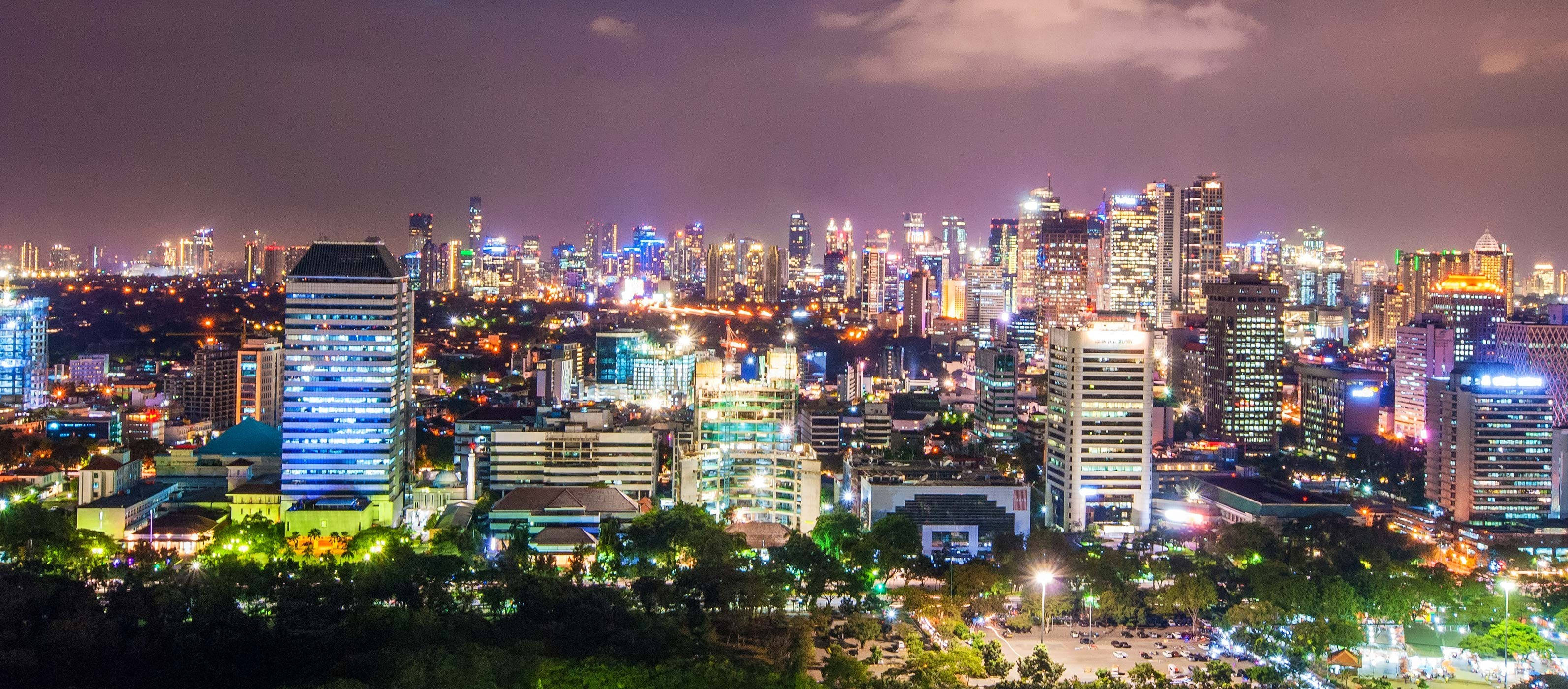 Jakarta 桌布 壁紙 — 令人眼花撩亂的夜景，高聳的摩天大樓在黑暗的天空中閃爍著霓虹燈光。