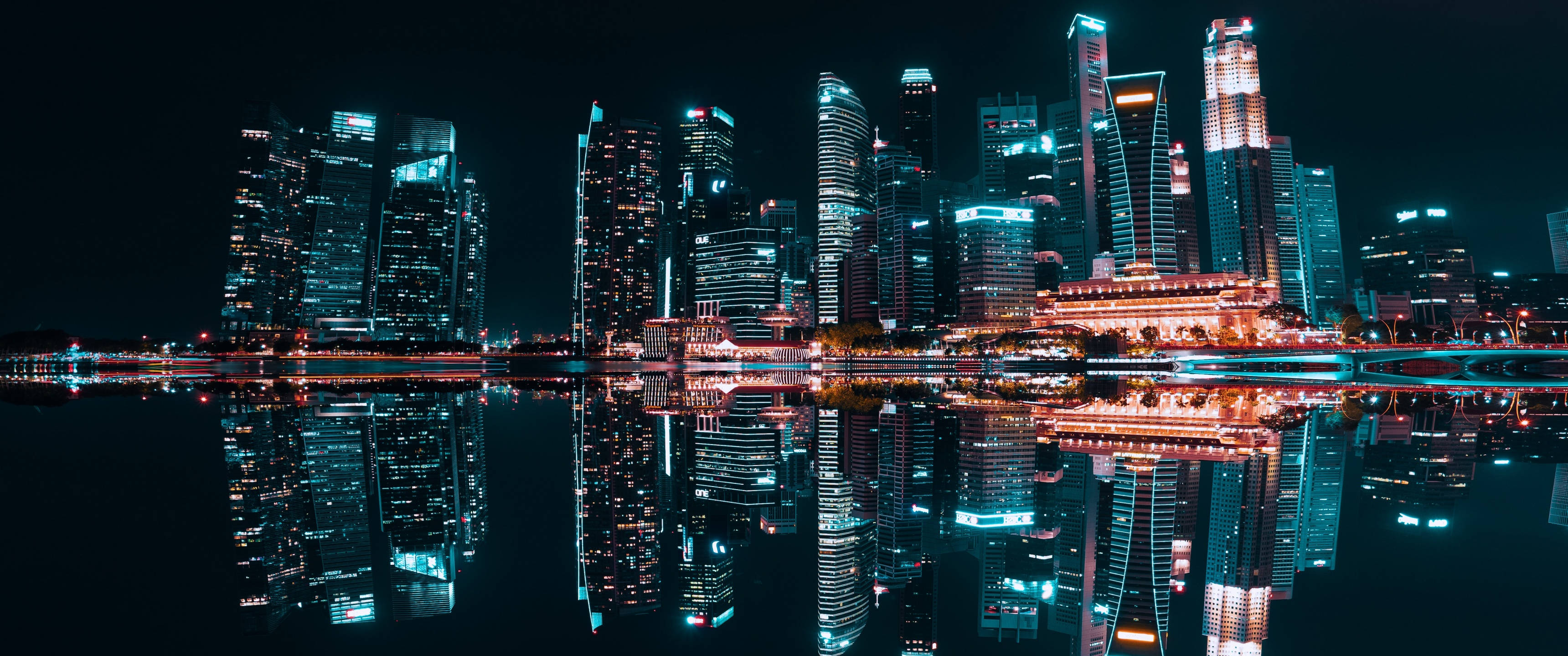 桌布 壁紙 — 令人眼花撩亂的夜景城市景觀，高聳的摩天大樓與充滿活力的霓虹燈完美地倒映在平靜的水面上。