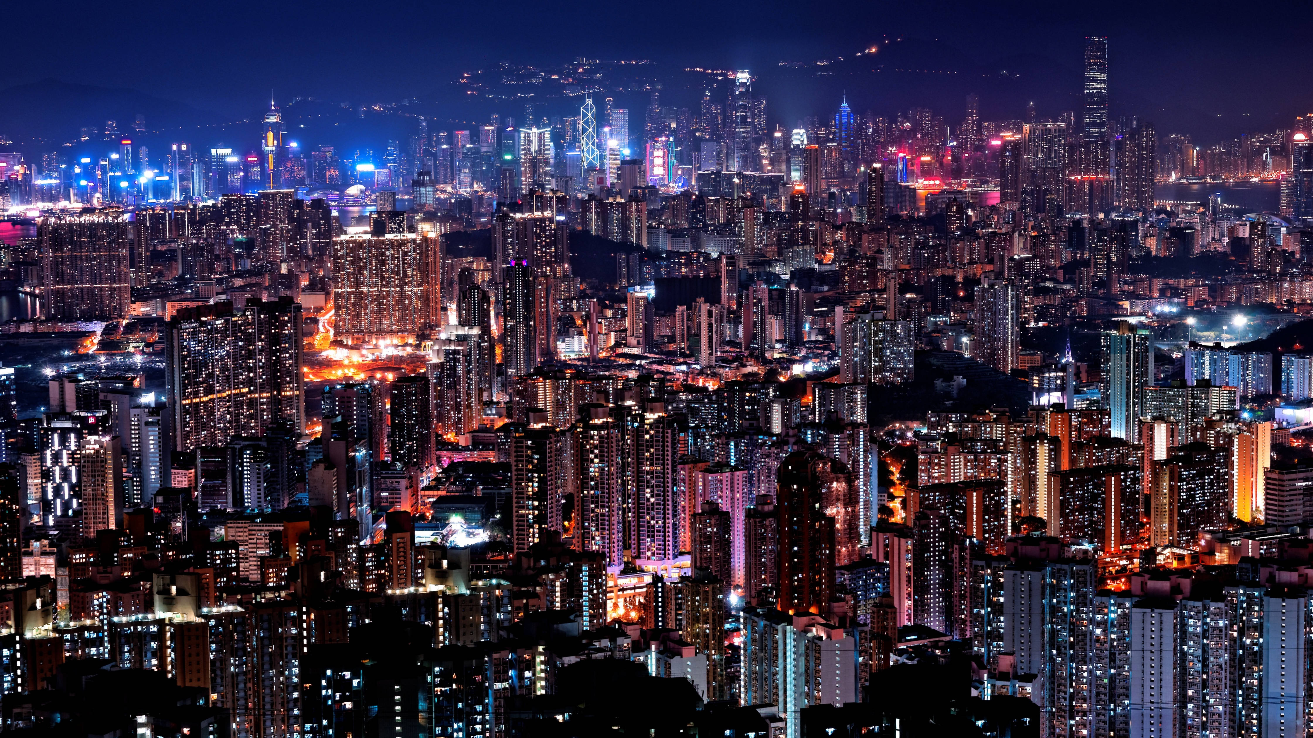 桌布 壁紙 — 令人眼花撩亂的夜景城市景觀，高聳的摩天大樓和密集的住宅建築閃爍著鮮豔的霓虹燈光。