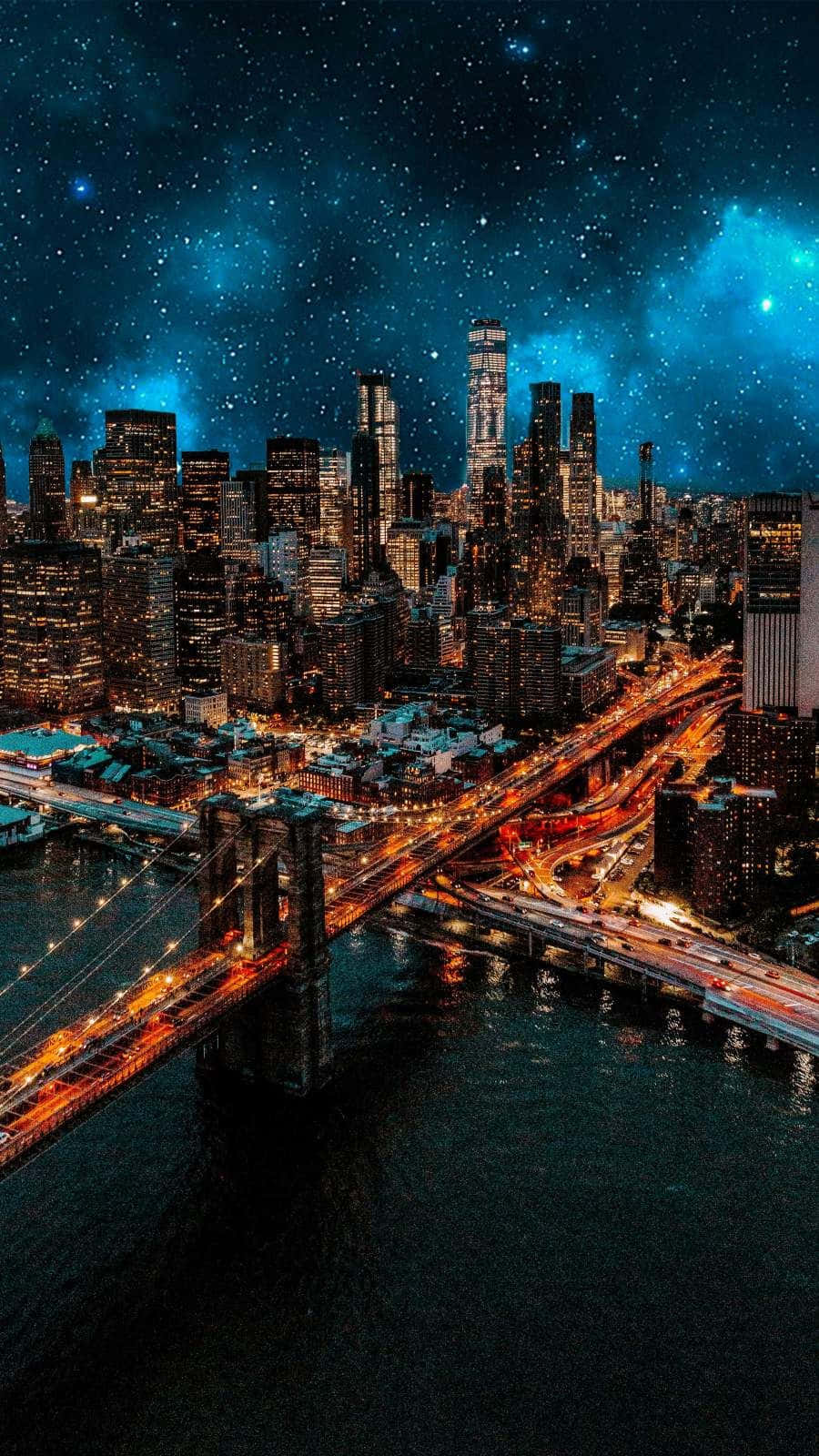 Lit iPhone 桌布 壁紙 — 令人眼花撩亂的夜間城市景觀，閃閃發光的摩天大樓和橫跨水面的橋樑上方星光燦爛的宇宙天空。