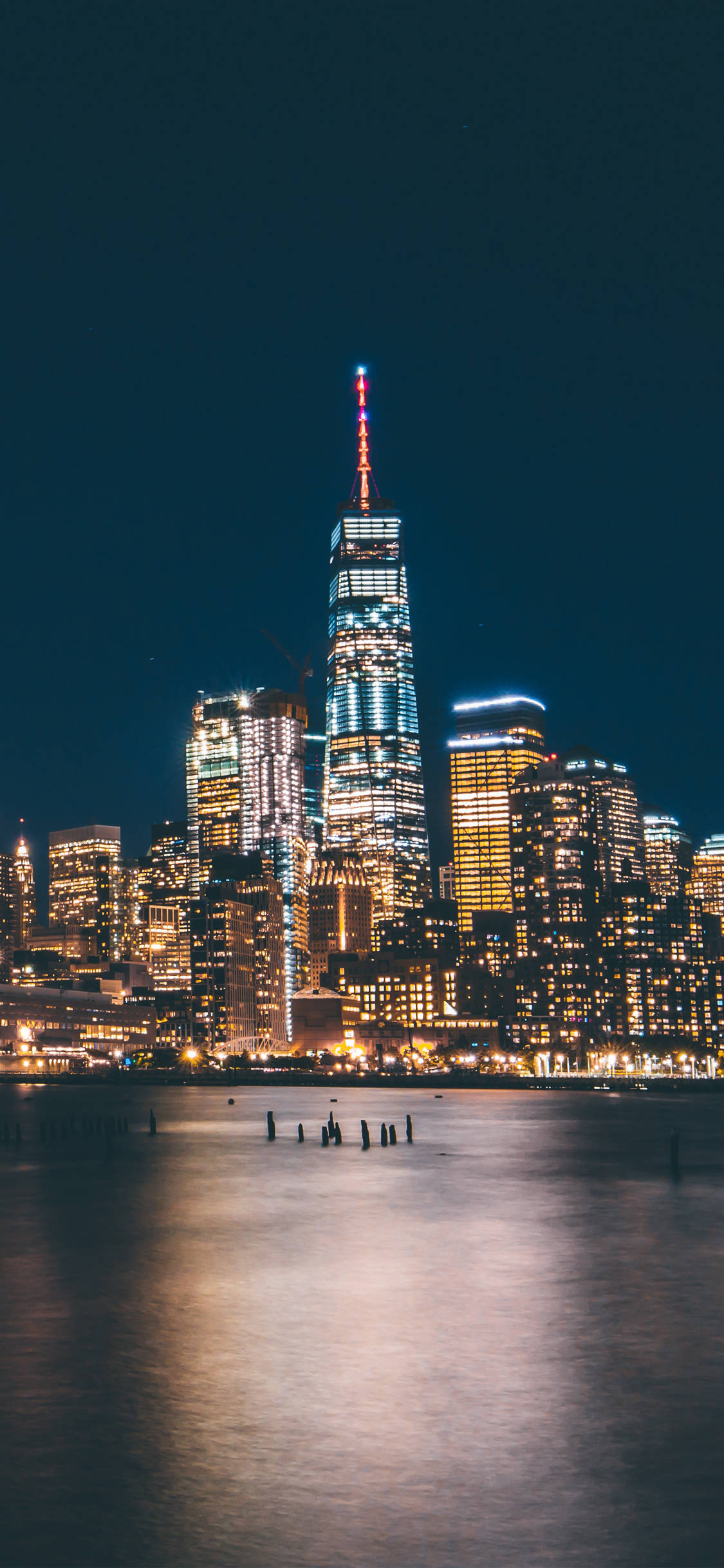 New 桌布 壁紙 — 令人驚嘆的夜景，照亮了世貿中心一號大樓和紐約市天際線，倒映在平靜的水面上。