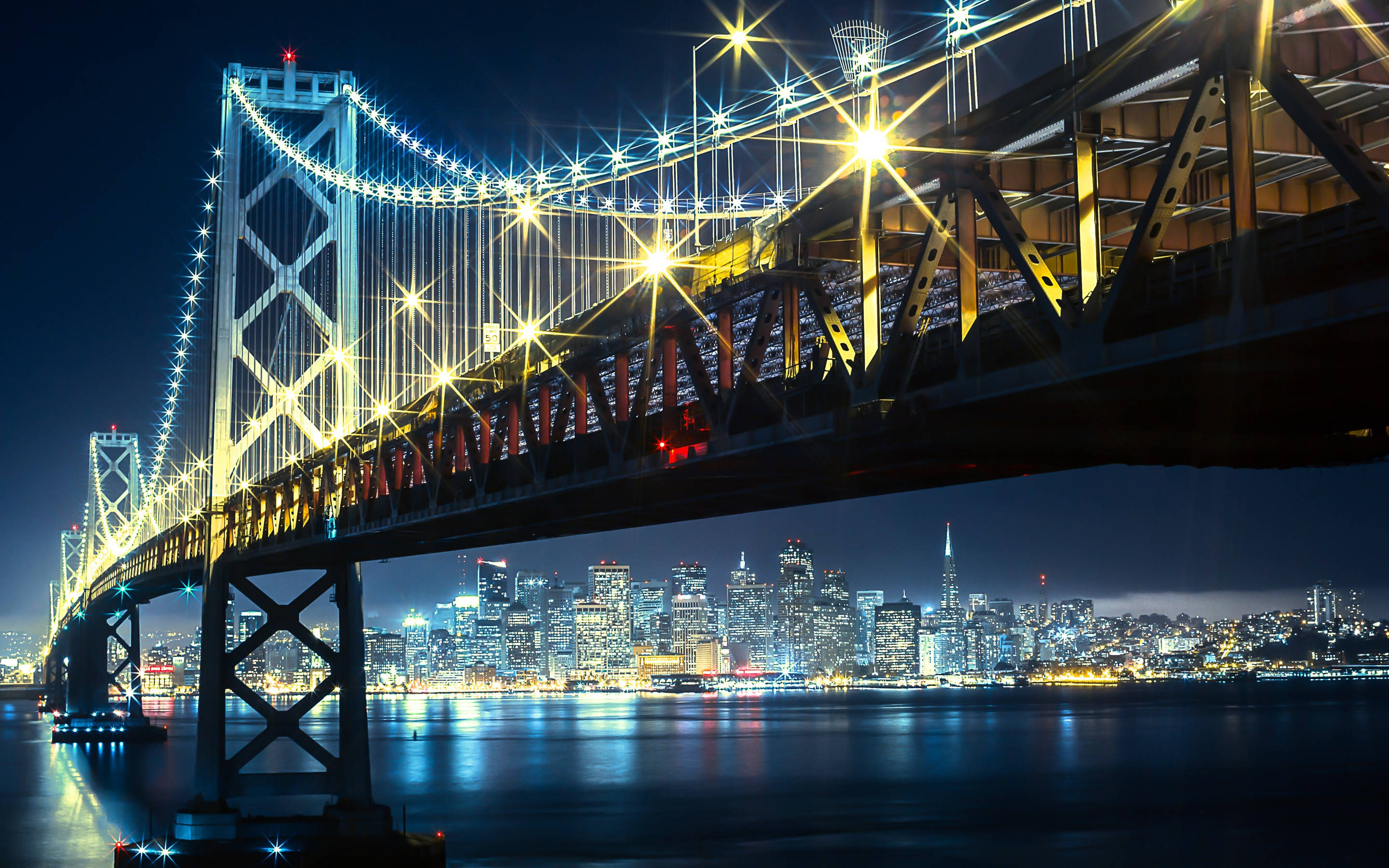 lights 桌布 壁紙 — 令人驚嘆的夜景，照亮的海灣大橋與舊金山閃爍的天際線倒映在平靜的水面上。