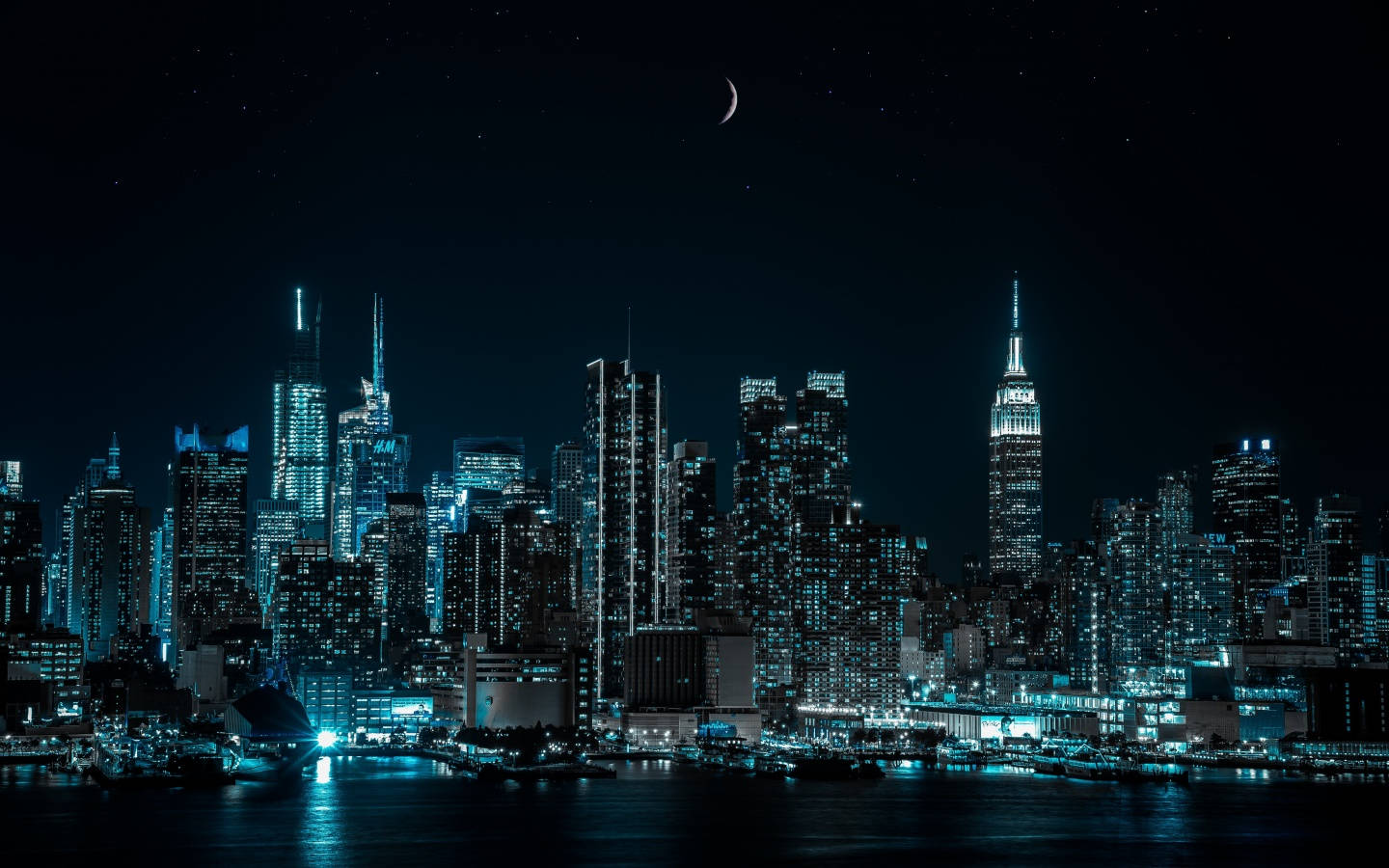 桌布 壁紙 — 令人驚嘆的夜景，發光的城市天際線上方有一彎新月，倒映在下方平靜的水面上。