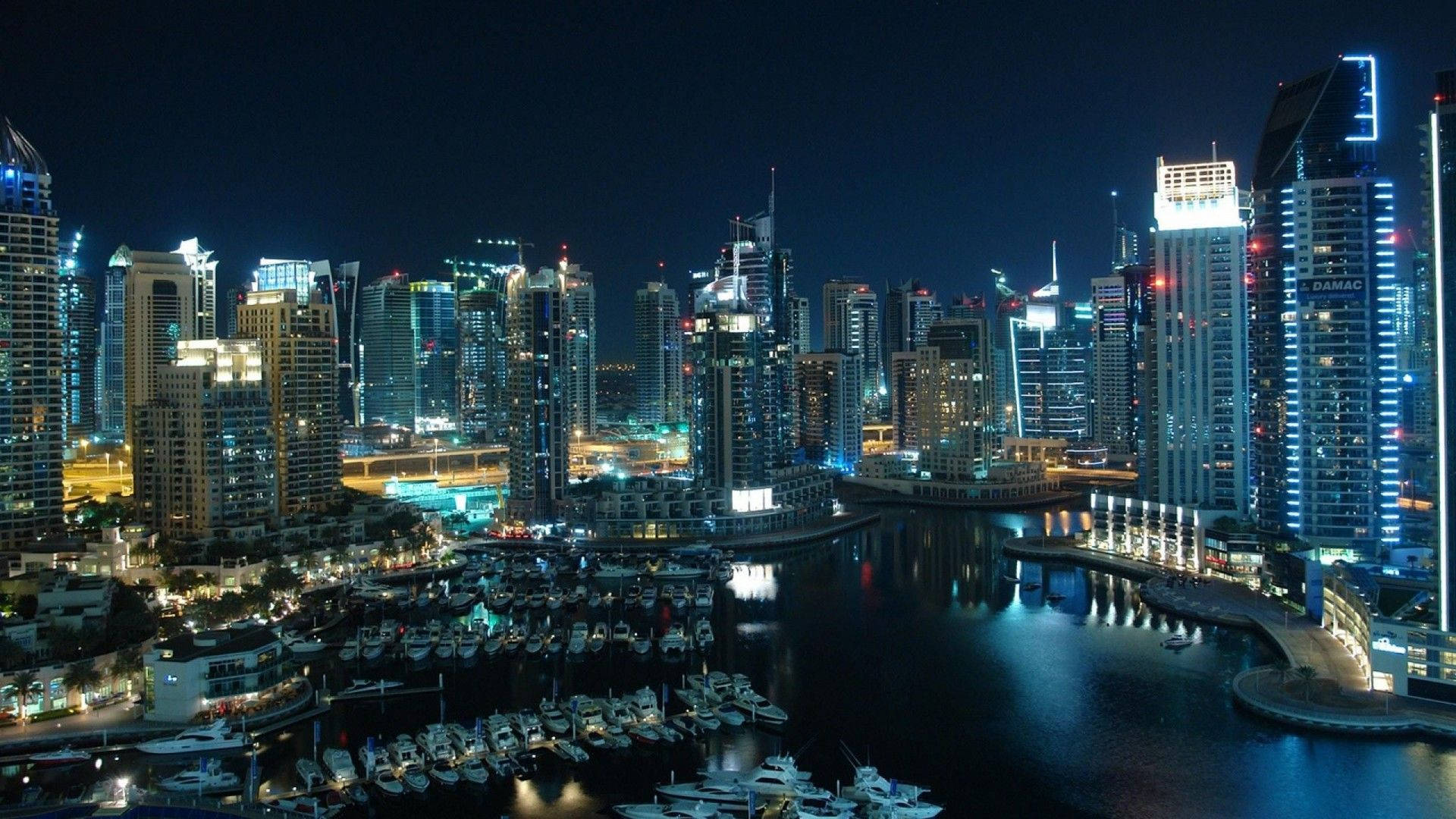 城市 桌布 壁紙 — 令人驚嘆的夜景，閃爍的摩天大樓倒映在停滿遊艇的碼頭中。