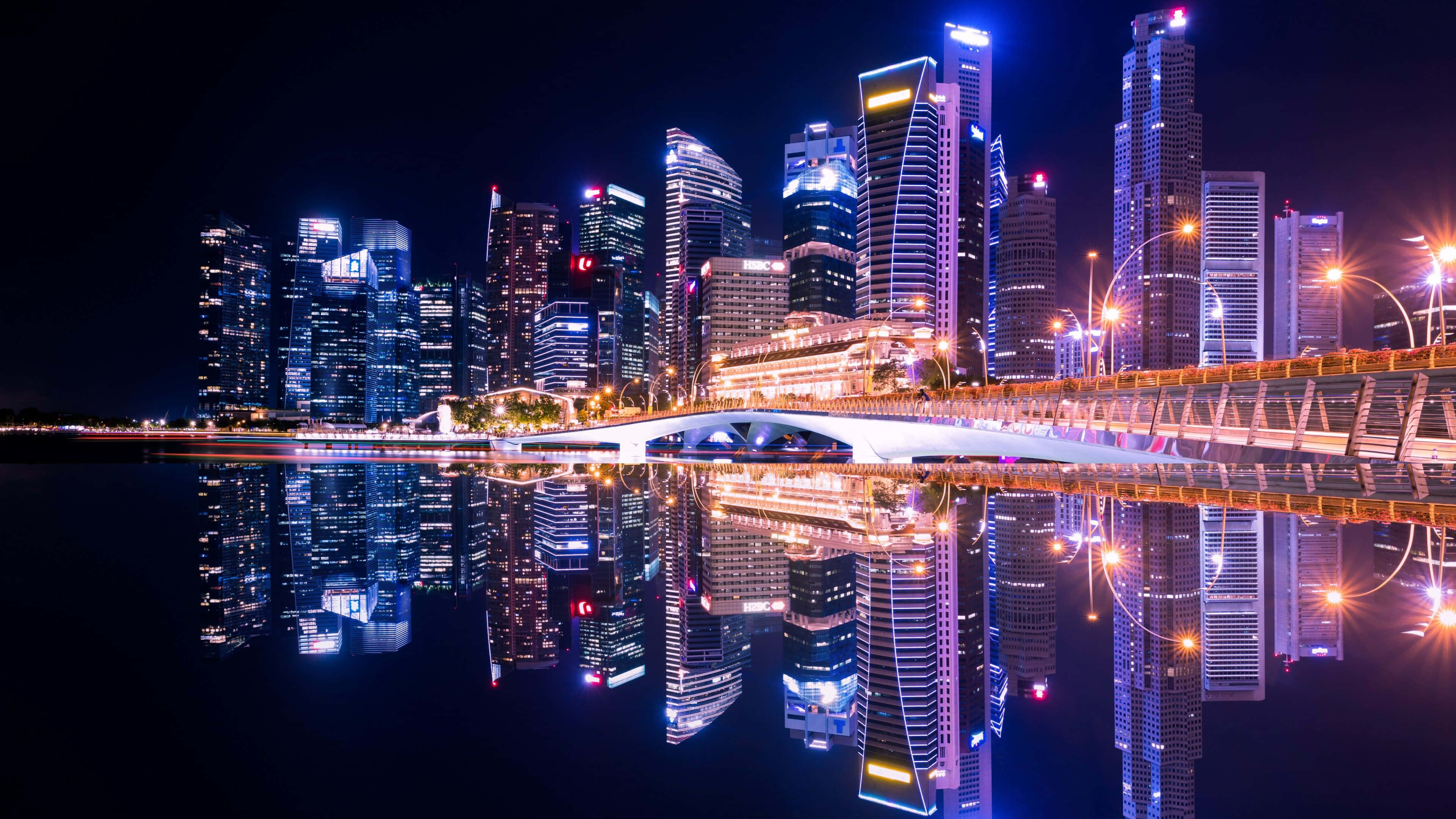 霓虹城市動態圖 桌布 壁紙 — 令人驚嘆的夜景，高聳的摩天大樓和發光的橋樑完美地倒映在平靜的水面上。