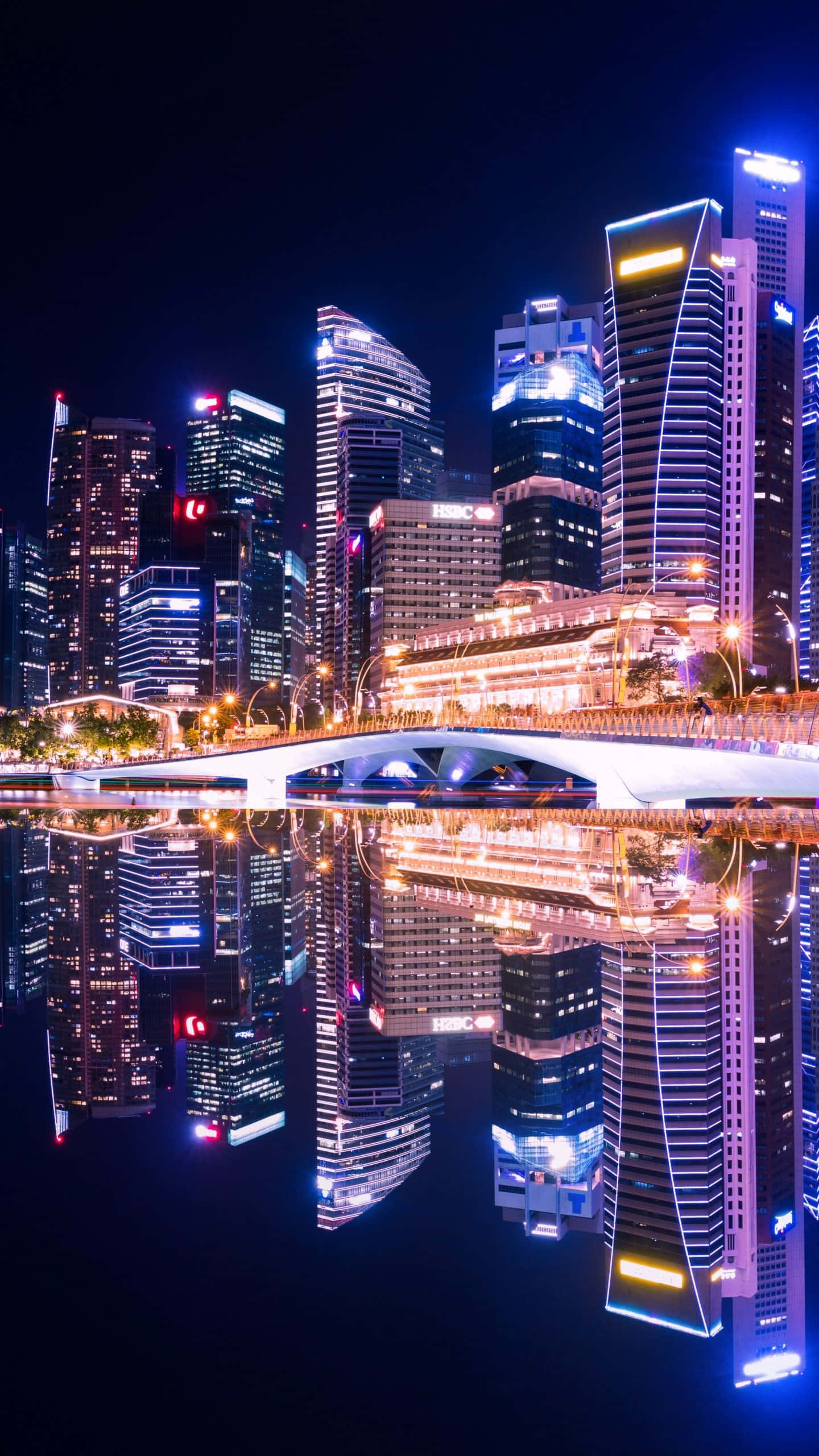 霓虹城市動態圖 桌布 壁紙 — 令人驚嘆的夜景，高聳的摩天大樓和發光的橋樑完美地倒映在平靜的水面上。