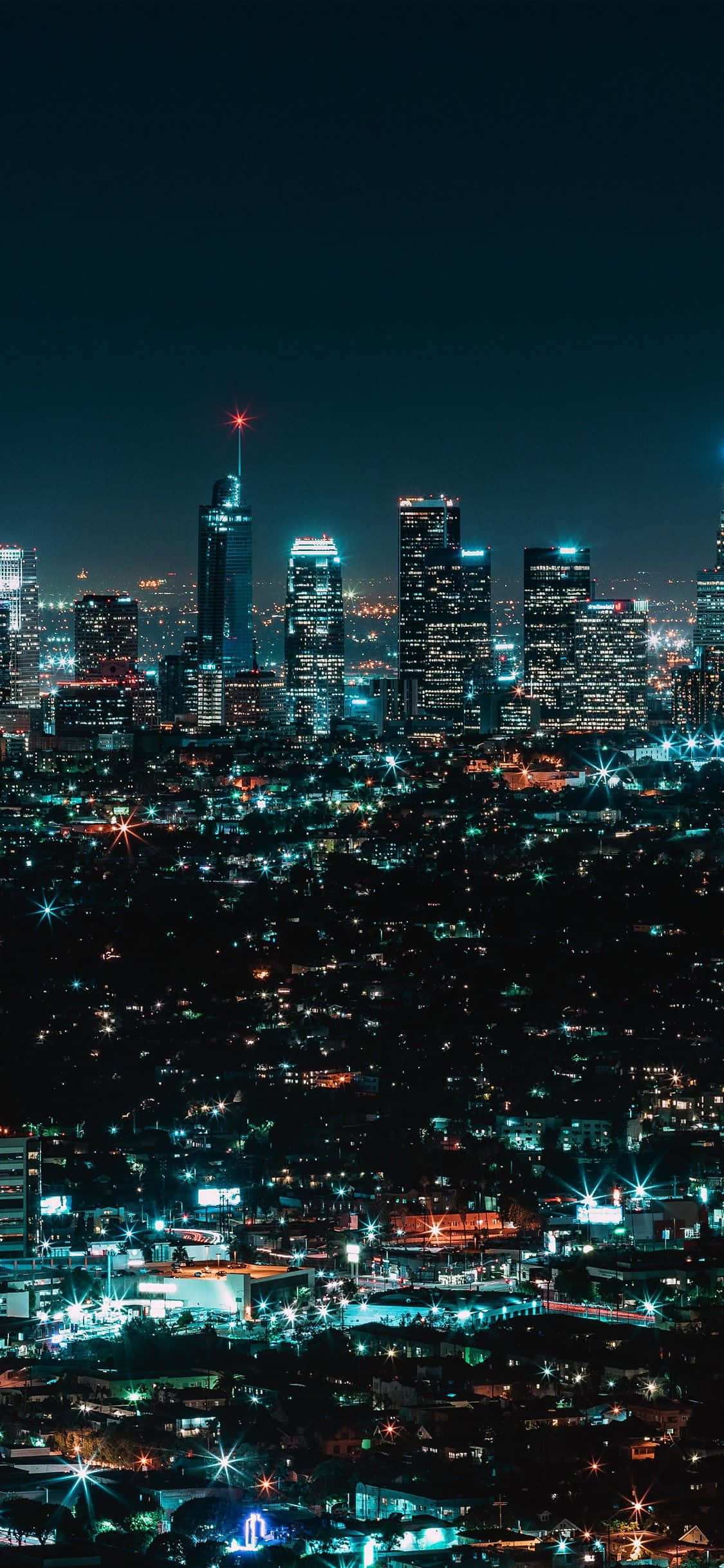 桌布 壁紙 — 令人驚嘆的夜景，高聳的摩天大樓在黑暗的天空中閃耀，周圍是閃爍的街燈海洋。
