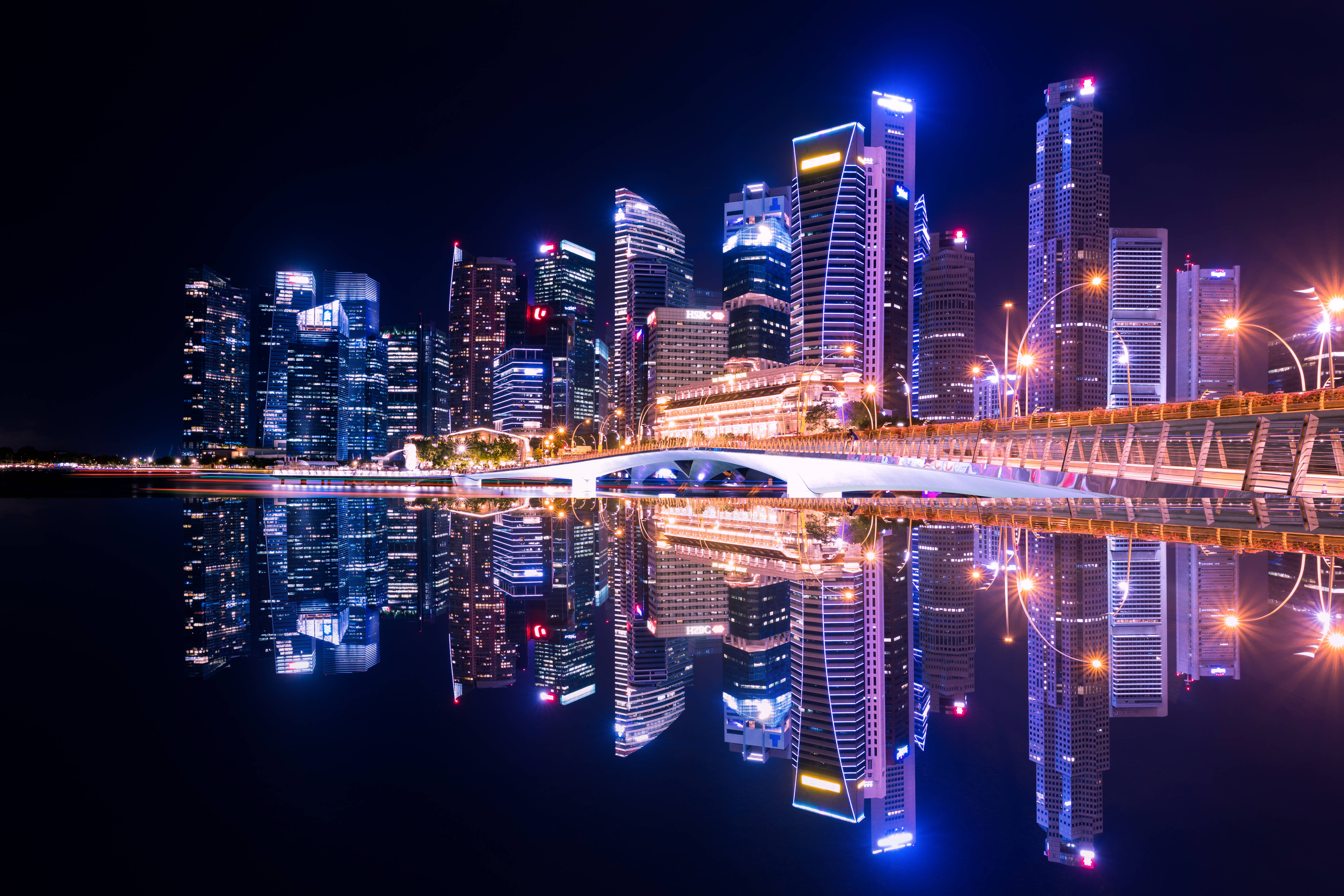 酷炫霓虹 桌布 壁紙 — 令人驚嘆的夜景城市景觀，燈火通明的摩天大樓和發光的橋樑完美地倒映在平靜的水面上。