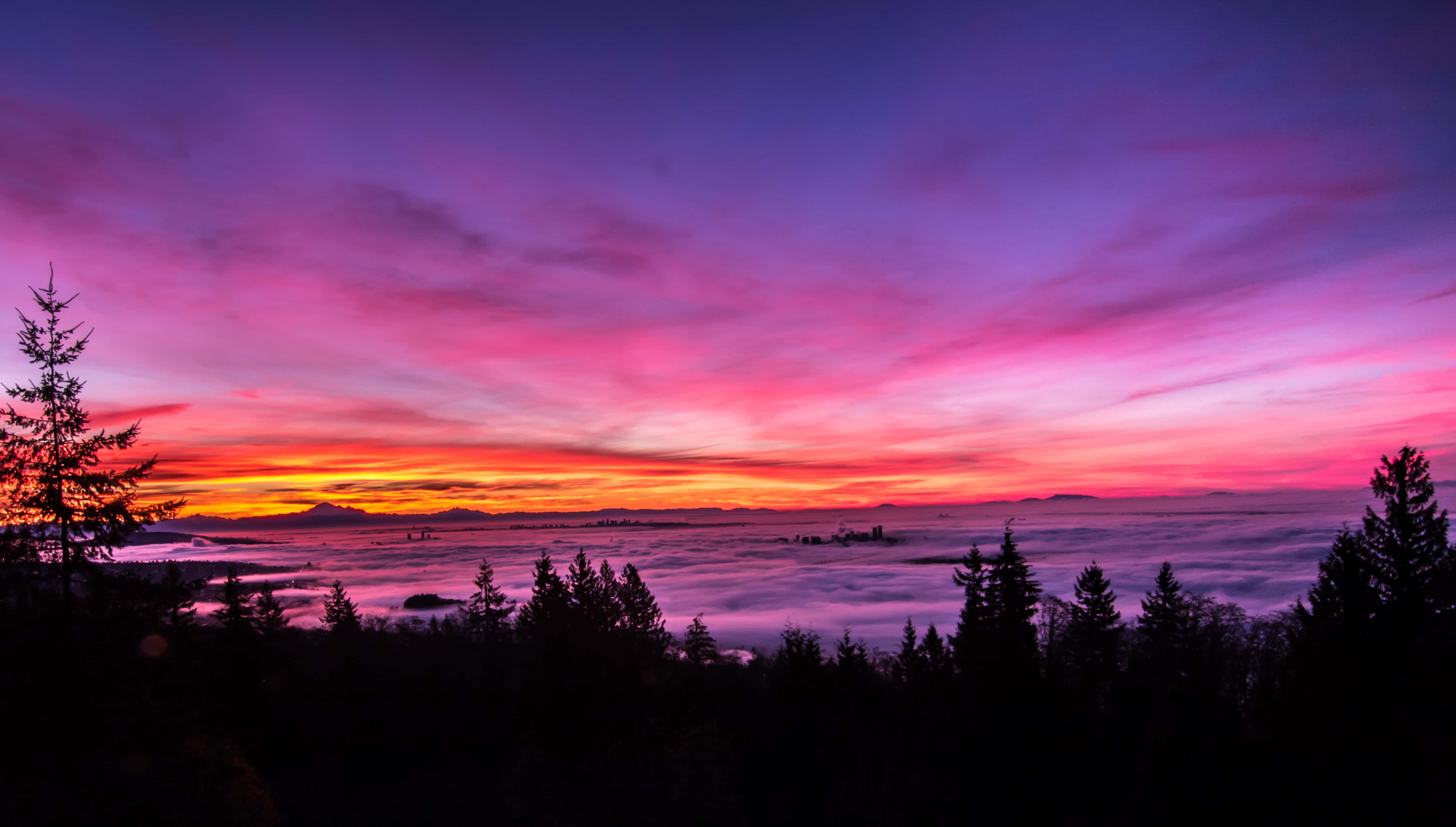 Sunset Landscape 桌布 壁紙 — 令人驚嘆的日落將天空染成火熱的橙色和深紫色，雲層覆蓋著下方的山谷。
